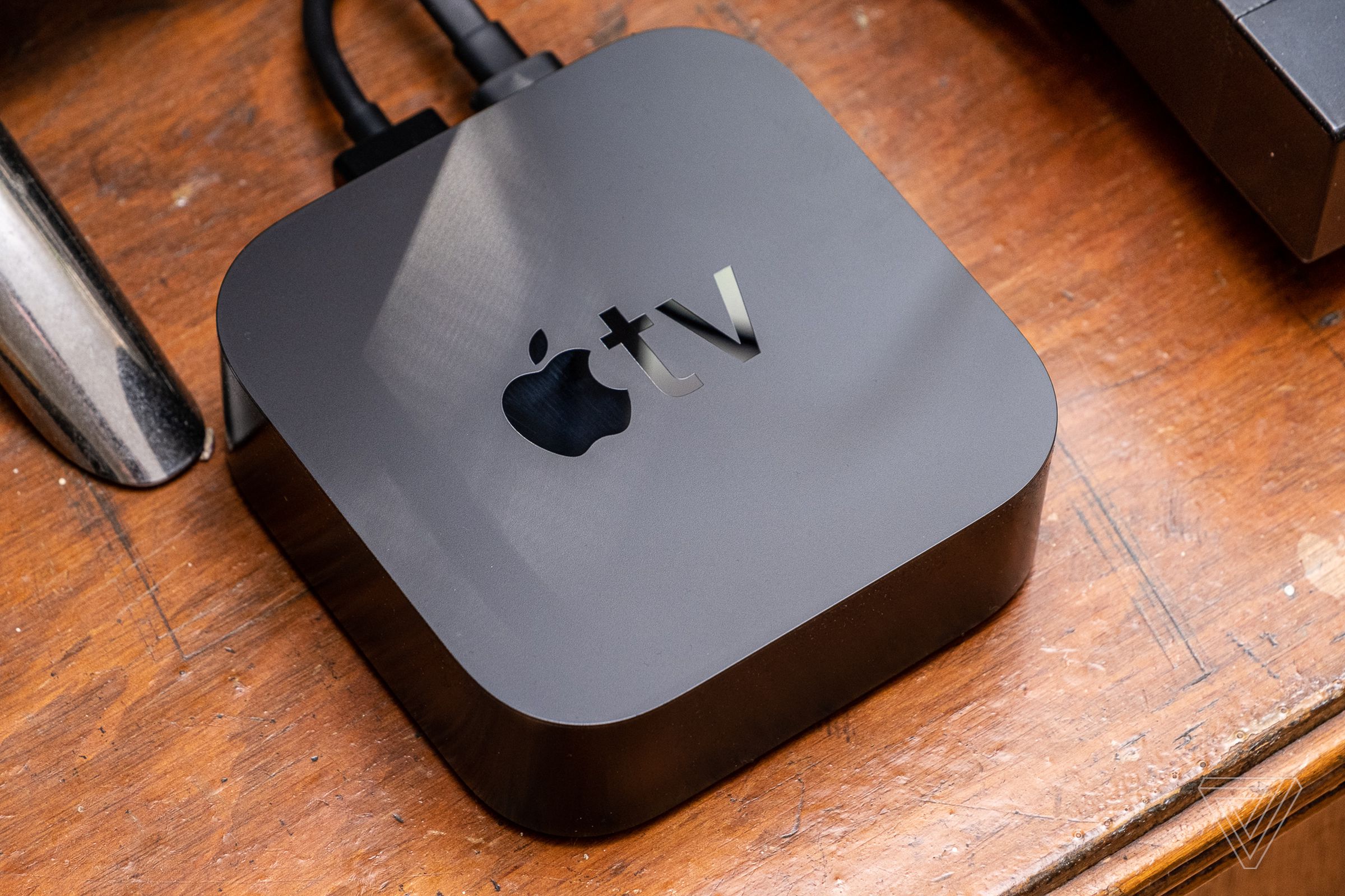 A photo of the Apple TV 4K set on top of a brown wooden surface.
