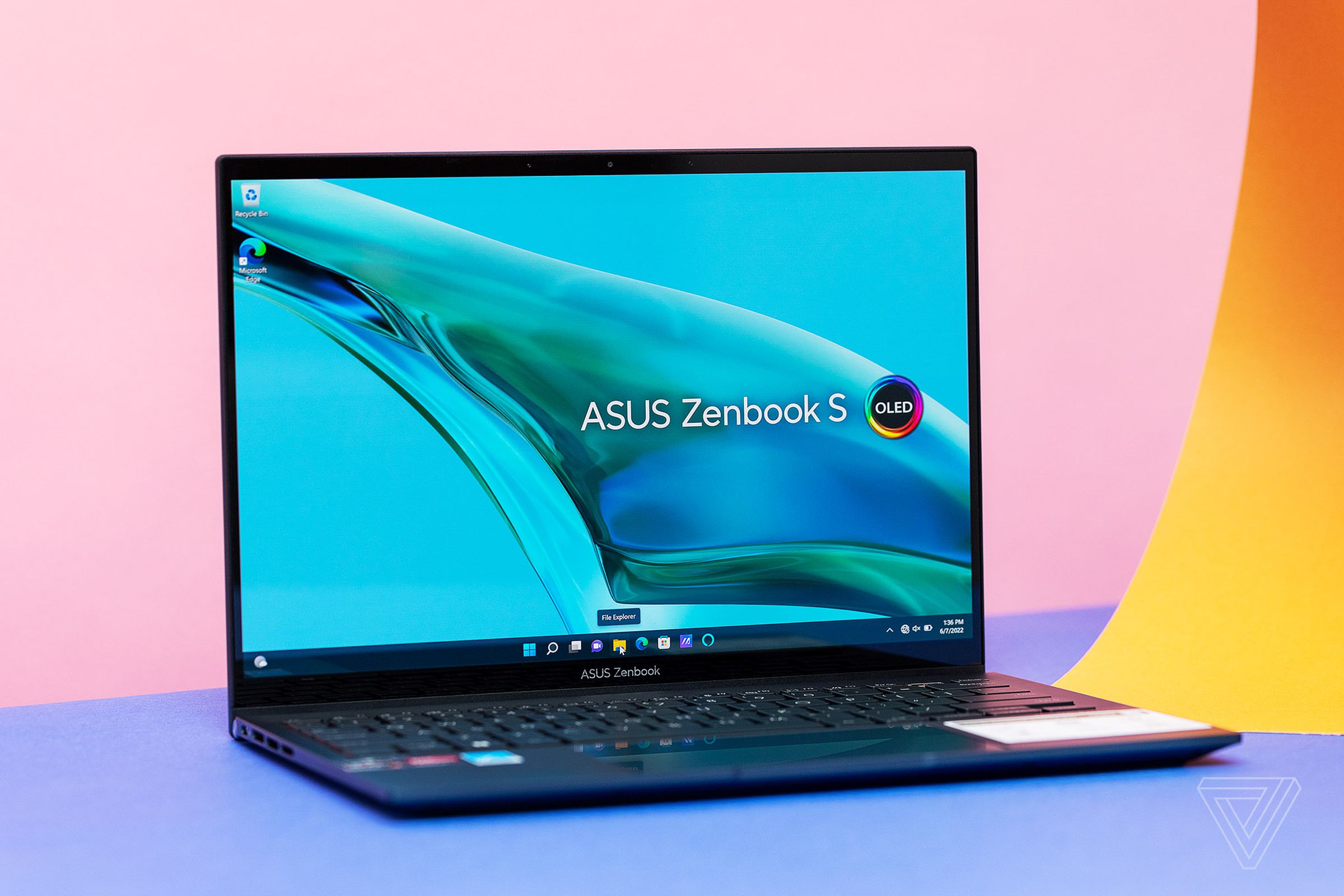 The Asus Zenbook S 13 OLED on a blue and pink background. The screen displays a stream of water on a blue background with the Asus Zenbook S OLED logo.