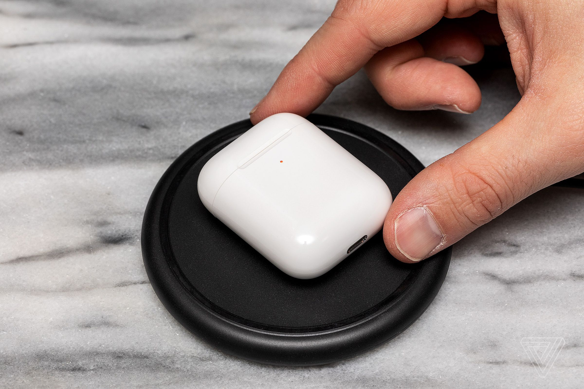 An AirPods case recharging on a wireless pad.