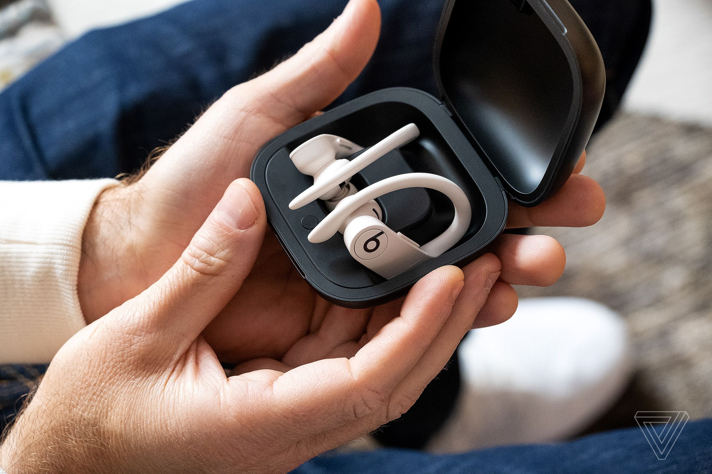 Powerbeats Pro earbuds pictured inside their case in someone’s hand.