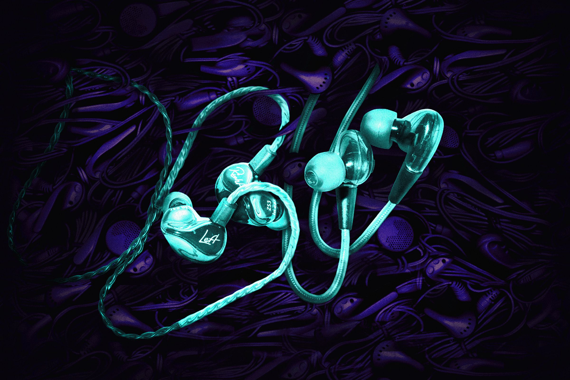 Two bright blue earbuds stand out against a background of darker, unidentifiable earbuds