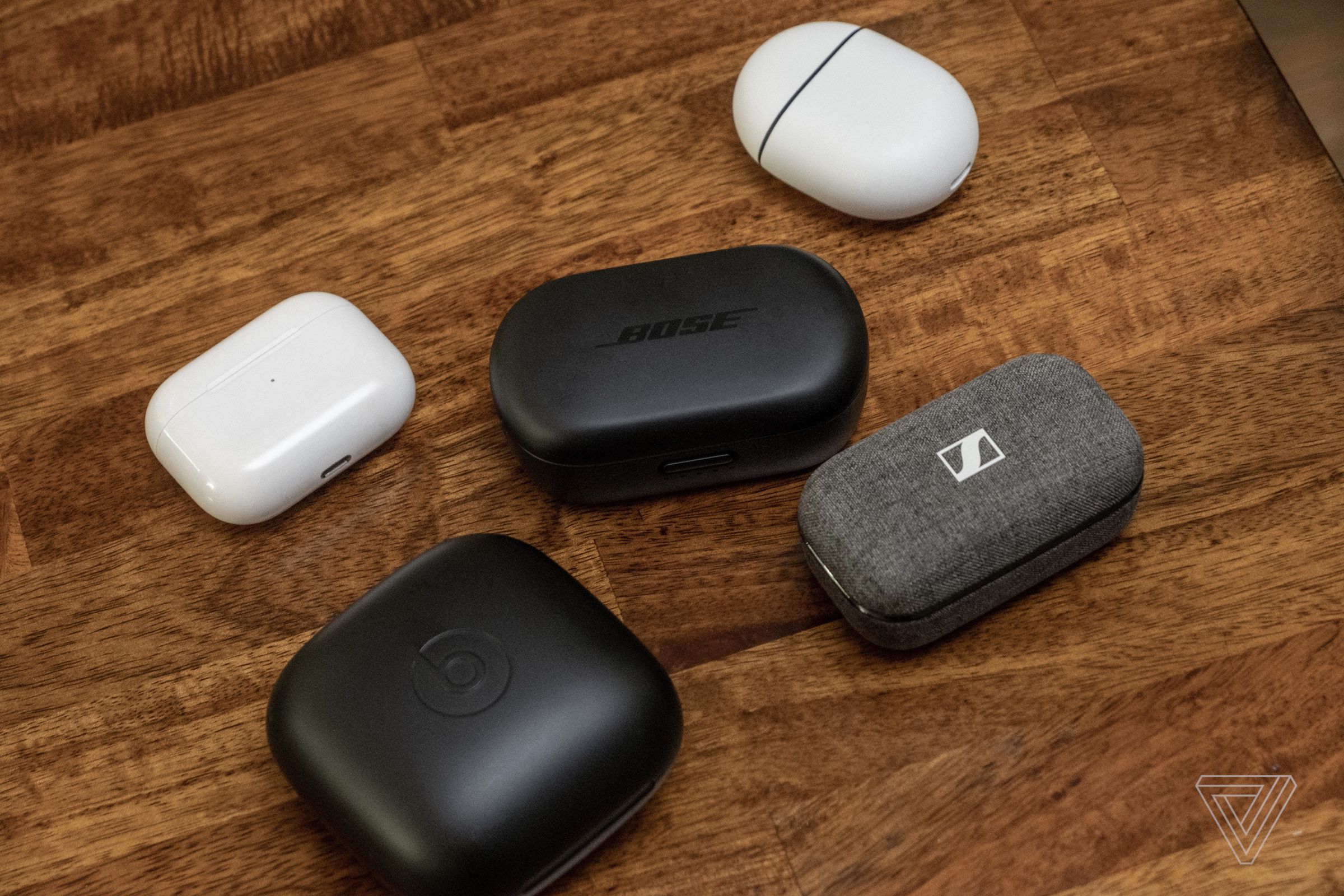 Bose’s QuietComfort Earbuds case next to cases for the AirPods, Pixel Buds, Powerbeats Pro, and Sennheiser Momentum True Wireless 2.