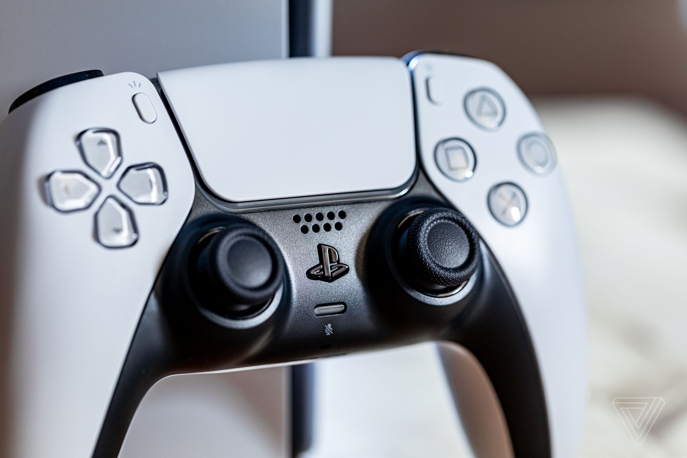 A close-up of a white DualSense controller resting against a PlayStation 5 console.