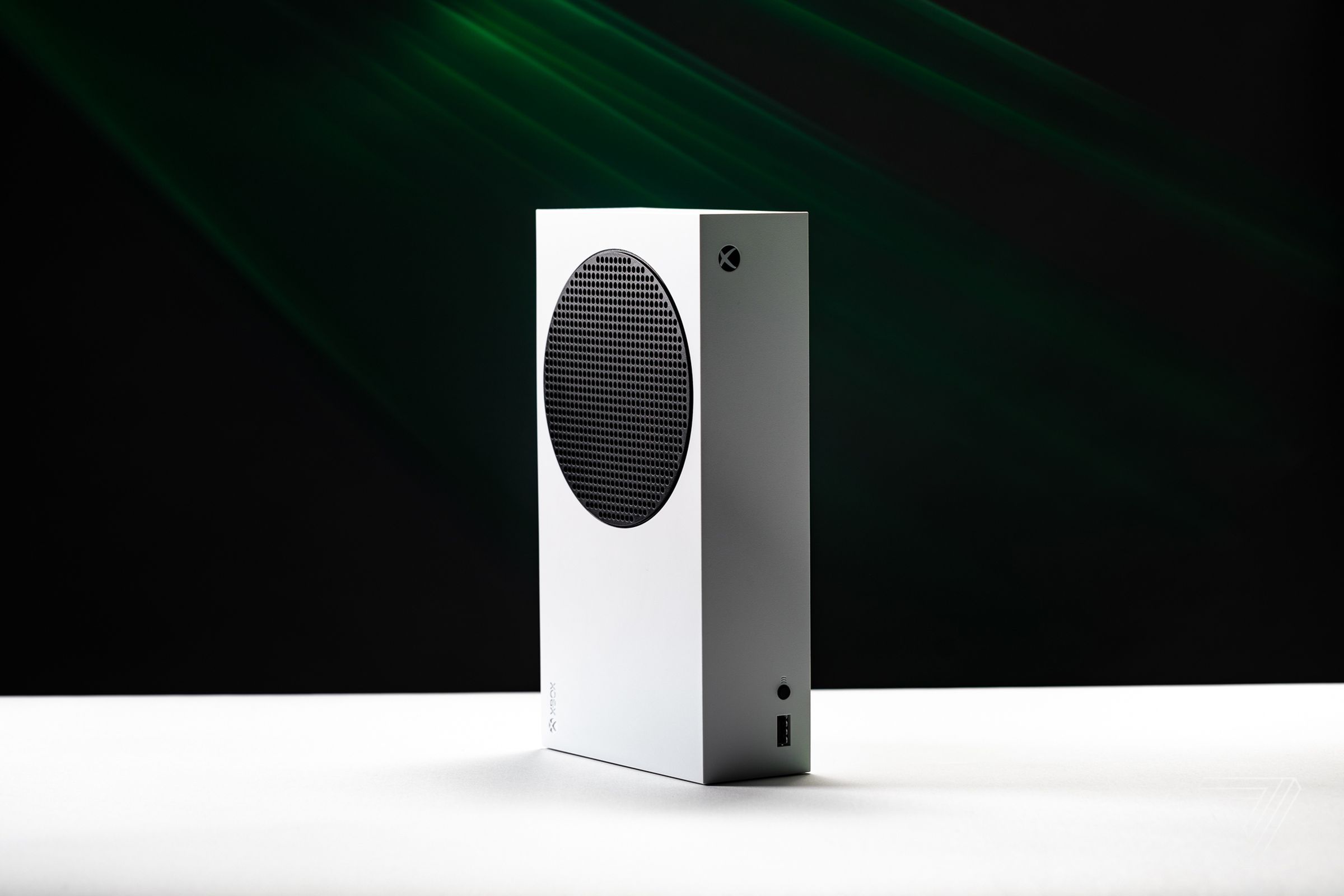 The white and black Xbox Series S console standing vertically on a white table in front of a black background.