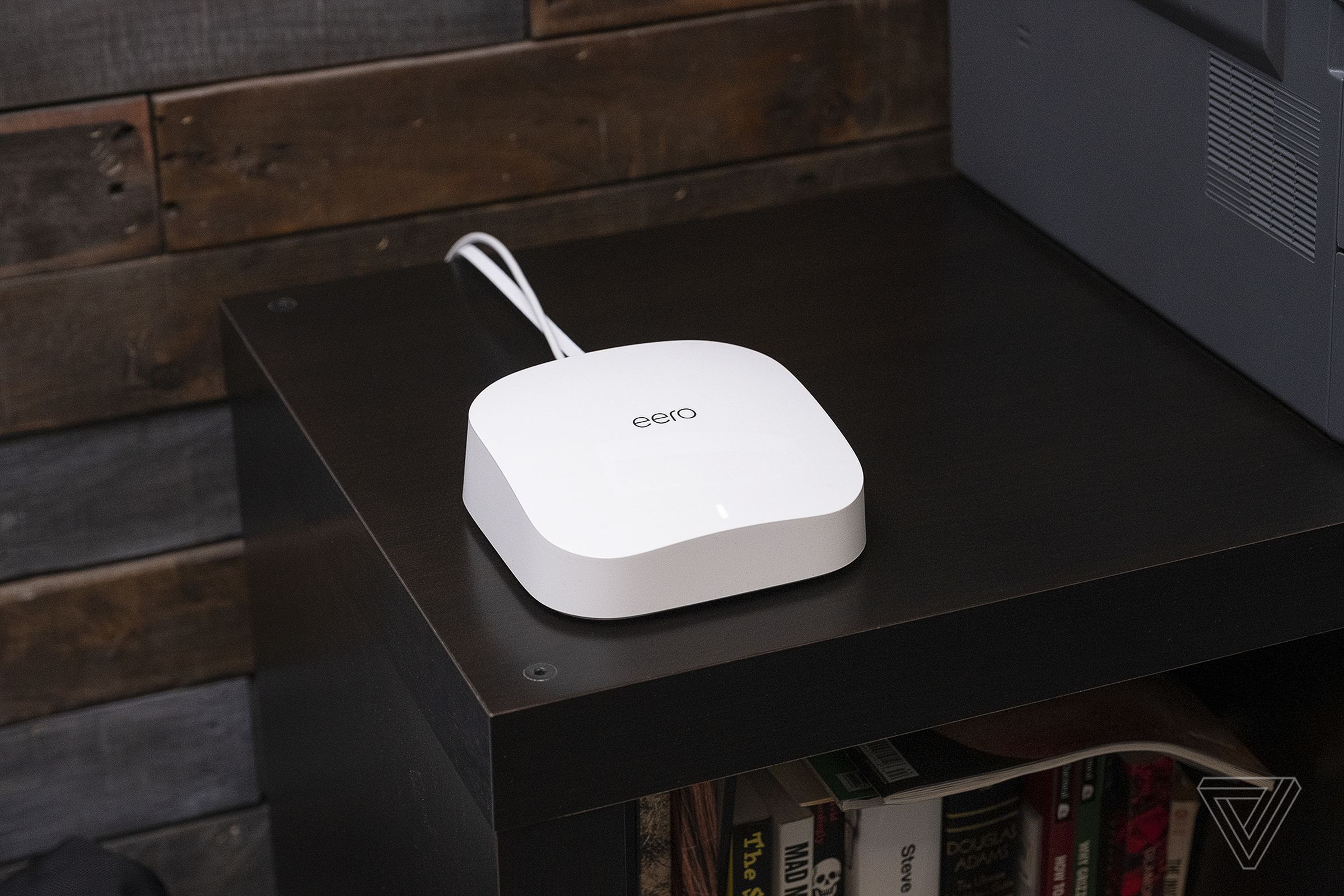 An Eero Pro 6 wireless Wi-Fi router sits on a wooden corner table.