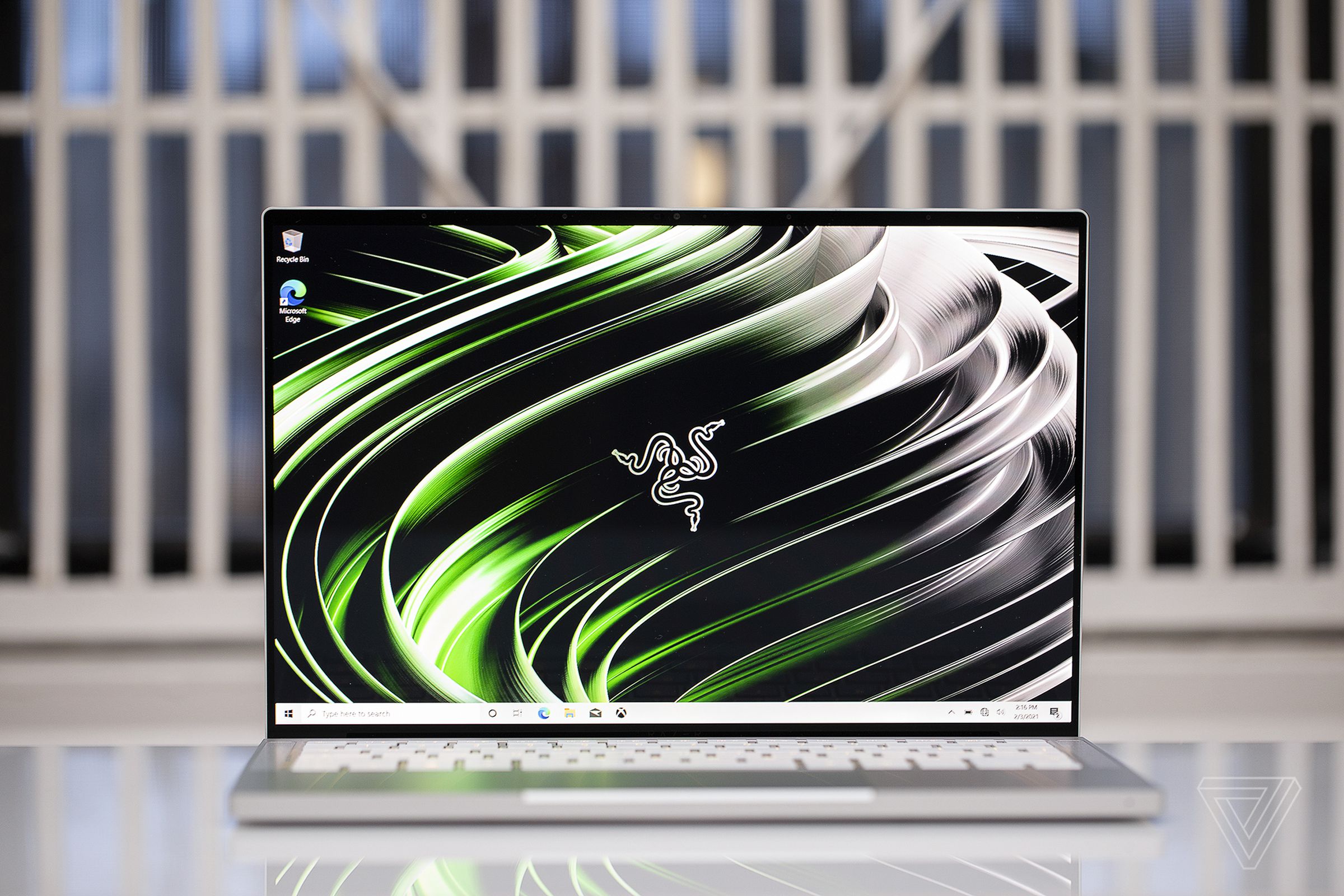 The Razer Book 13 open. The screen displays the Razer logo on a green and black background.
