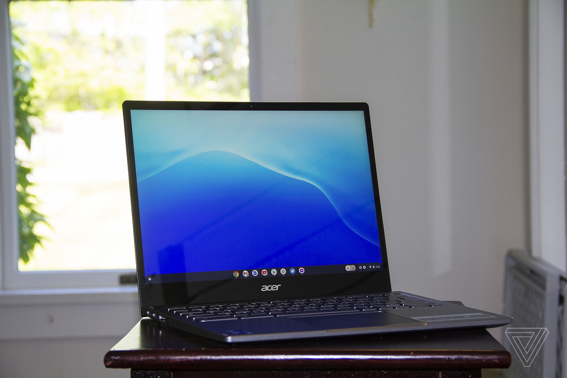 The Acer Chromebook Spin 713 open on a table angled to the right. The screen displays a blue background.