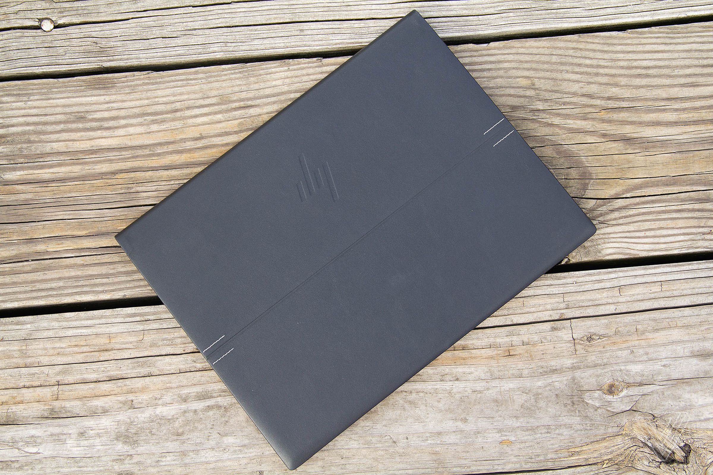 The HP Elite Folio closed on a wooden deck seen from above.