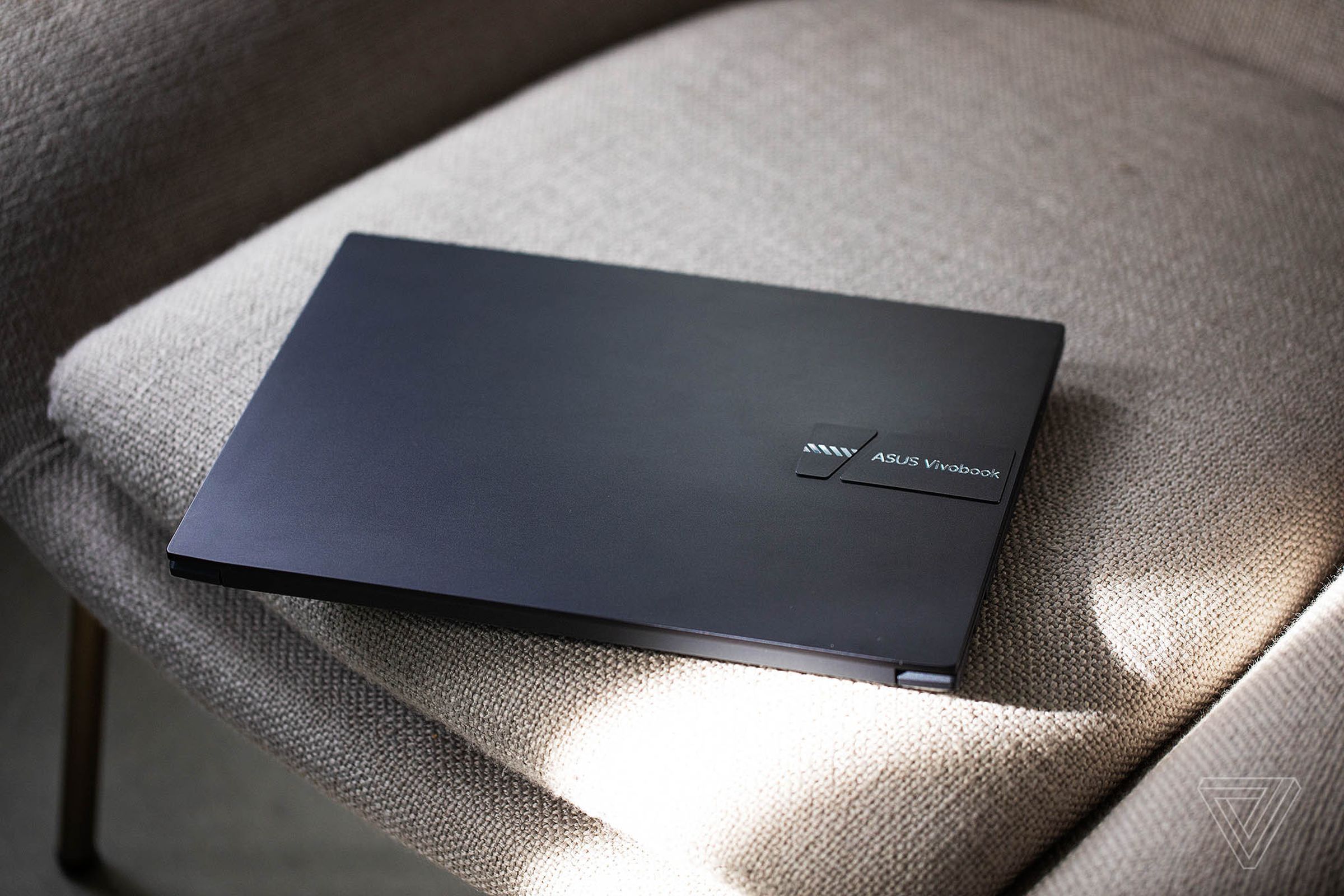 The Asus Vivobook Pro 14 closed, seen from above, on a white plush chair.