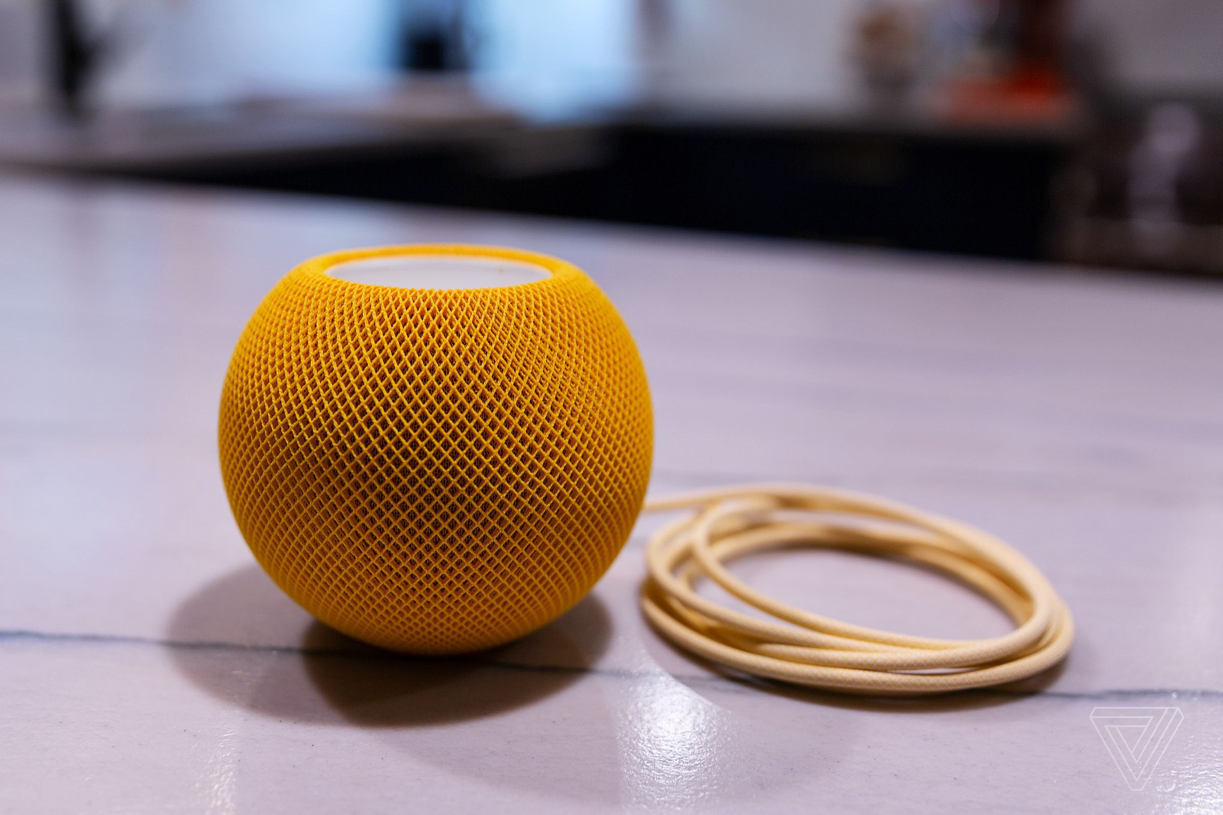 A photo of Apple’s yellow HomePod Mini speaker.