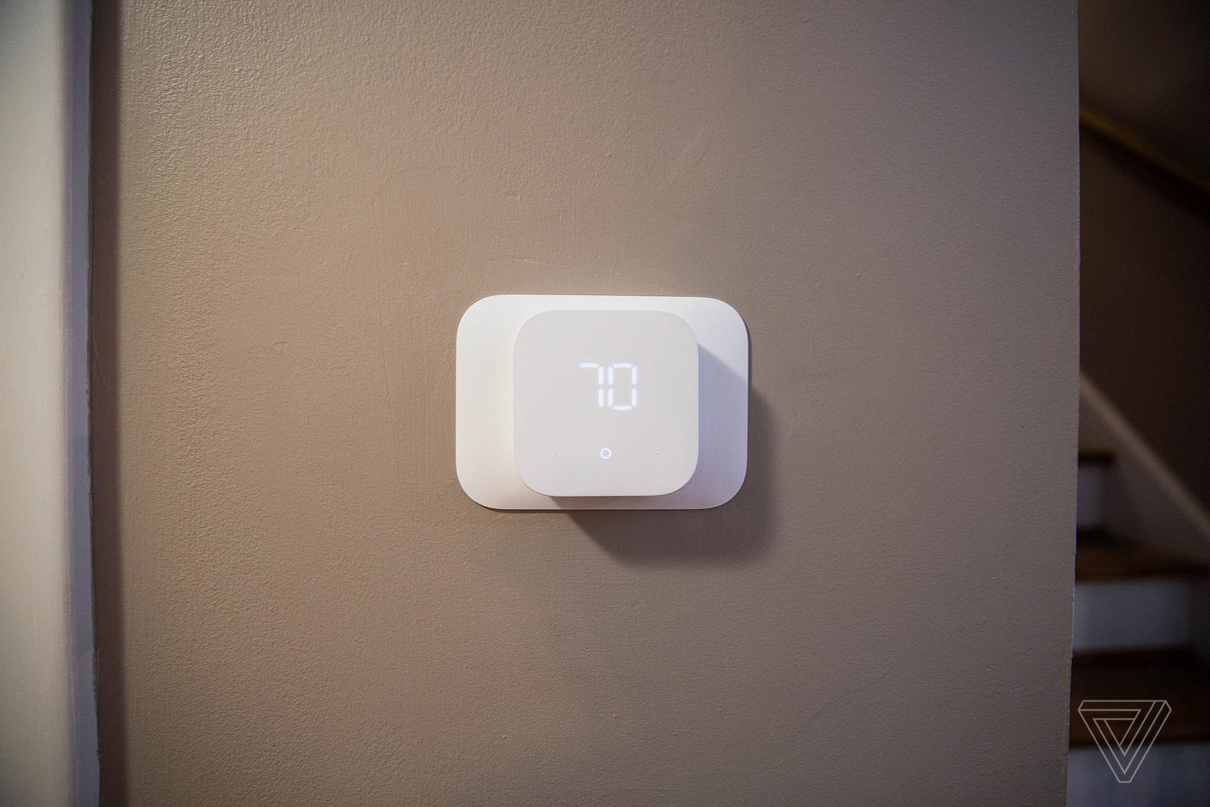 The white Amazon Smart Thermostat mounted to a wall.