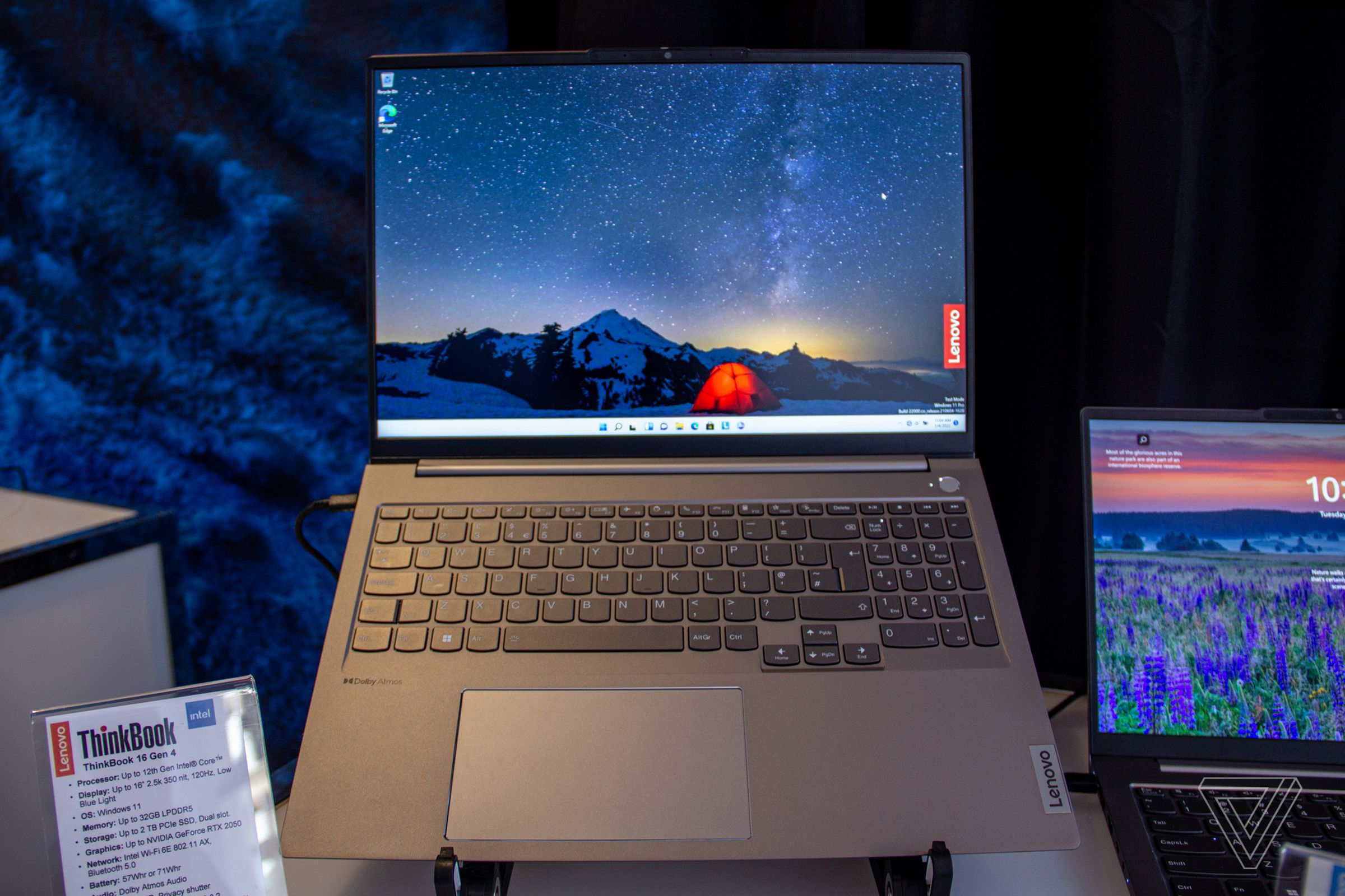 The Lenovo ThinkBook 16 Gen 4 on an angled stand, open. The screen displays a night outdoor scene with a small red tent in the center and the Lenovo logo on the right side.