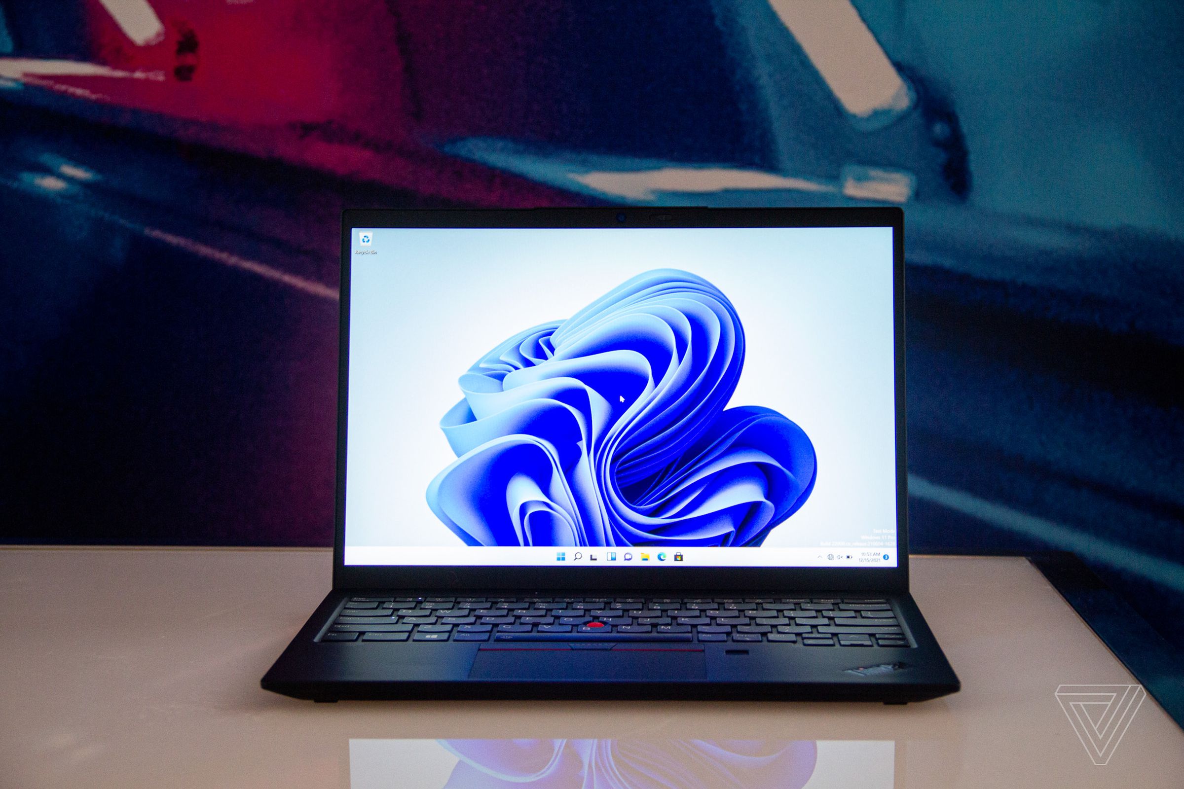 The ThinkPad X1 Nano 2nd-Gen open on white table. The screen displays a blue swirl on a white background.