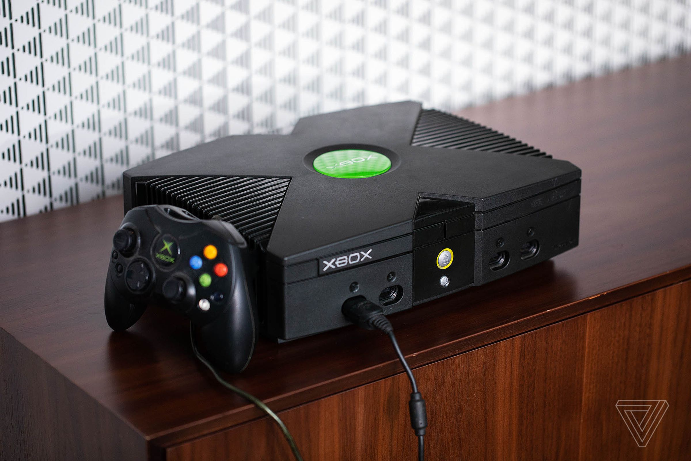 An original Xbox with an Xbox controller set next to it.