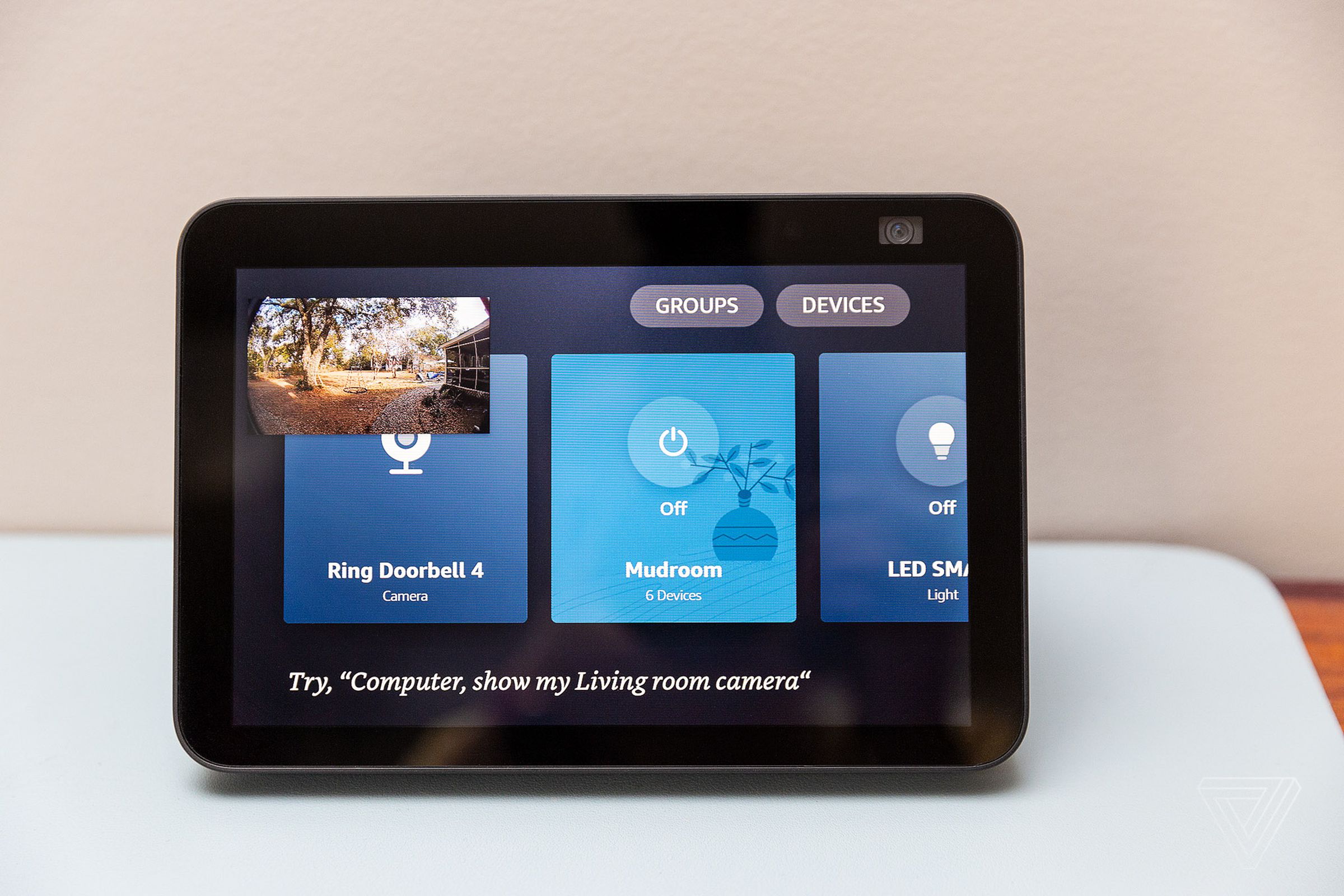 An Echo Show 8 with a live stream from a doorbell in picture-in-picture and the smart home control panel open on the main screen.