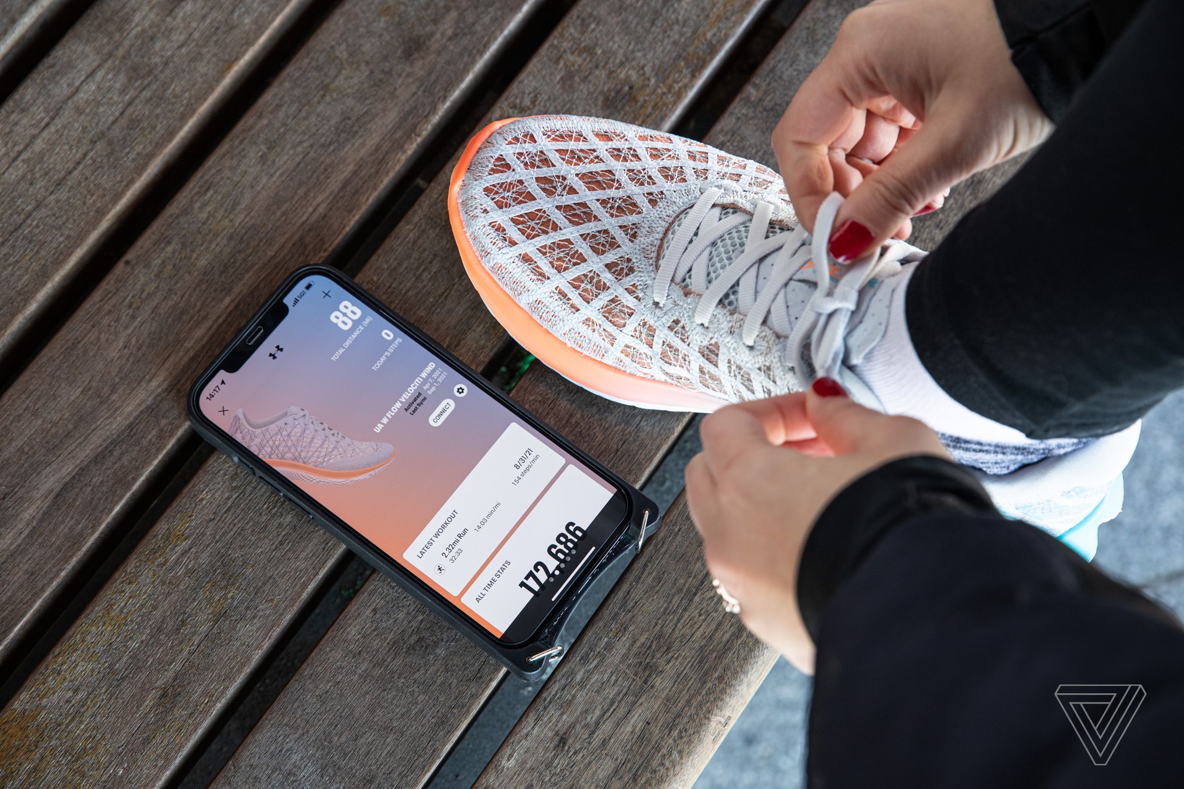 Person tying shoe next to a phone with the MapMyRun app pulled up