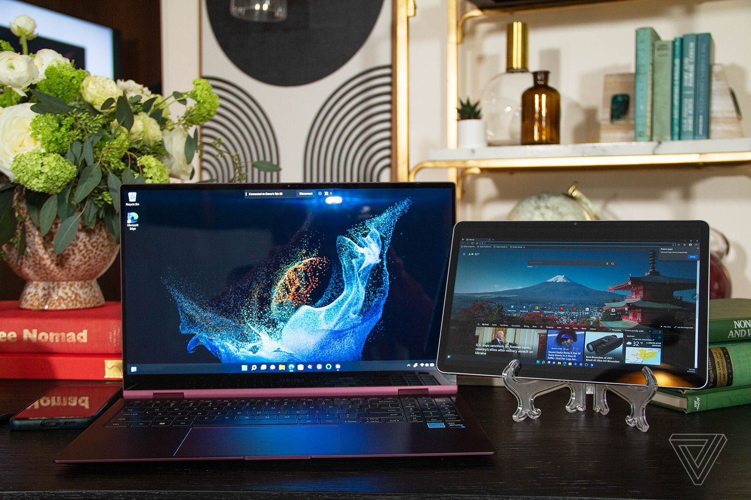 The Samsung Galaxy Book 2 Pro 360 next to a Samsung Galaxy Tab S8. The Galaxy Book displays a blue supernova on a black background. The Tab S8 displays a Microsoft Edge homepage.