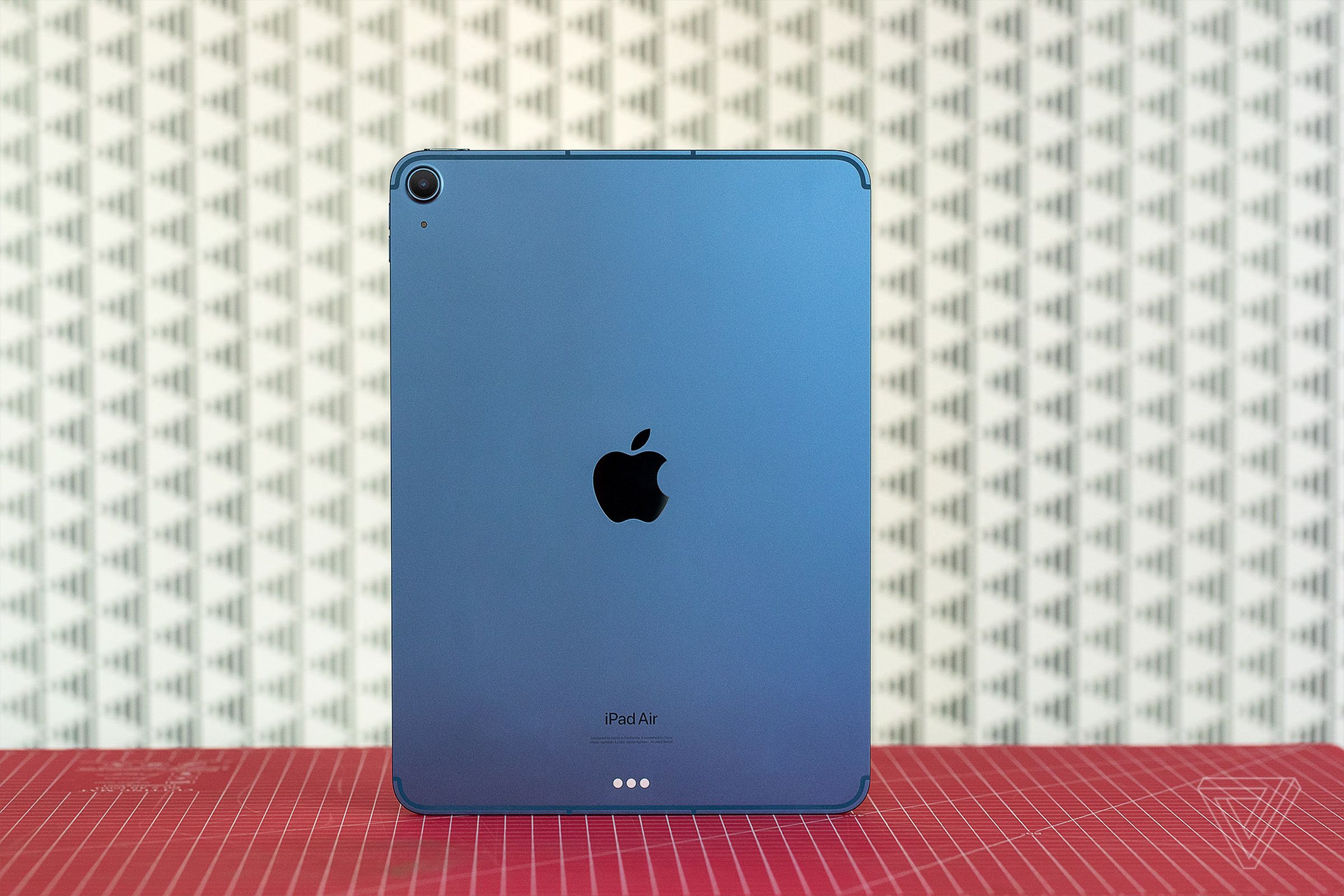 The rear of the 2022 iPad Air, in blue, in front of a patterned background.