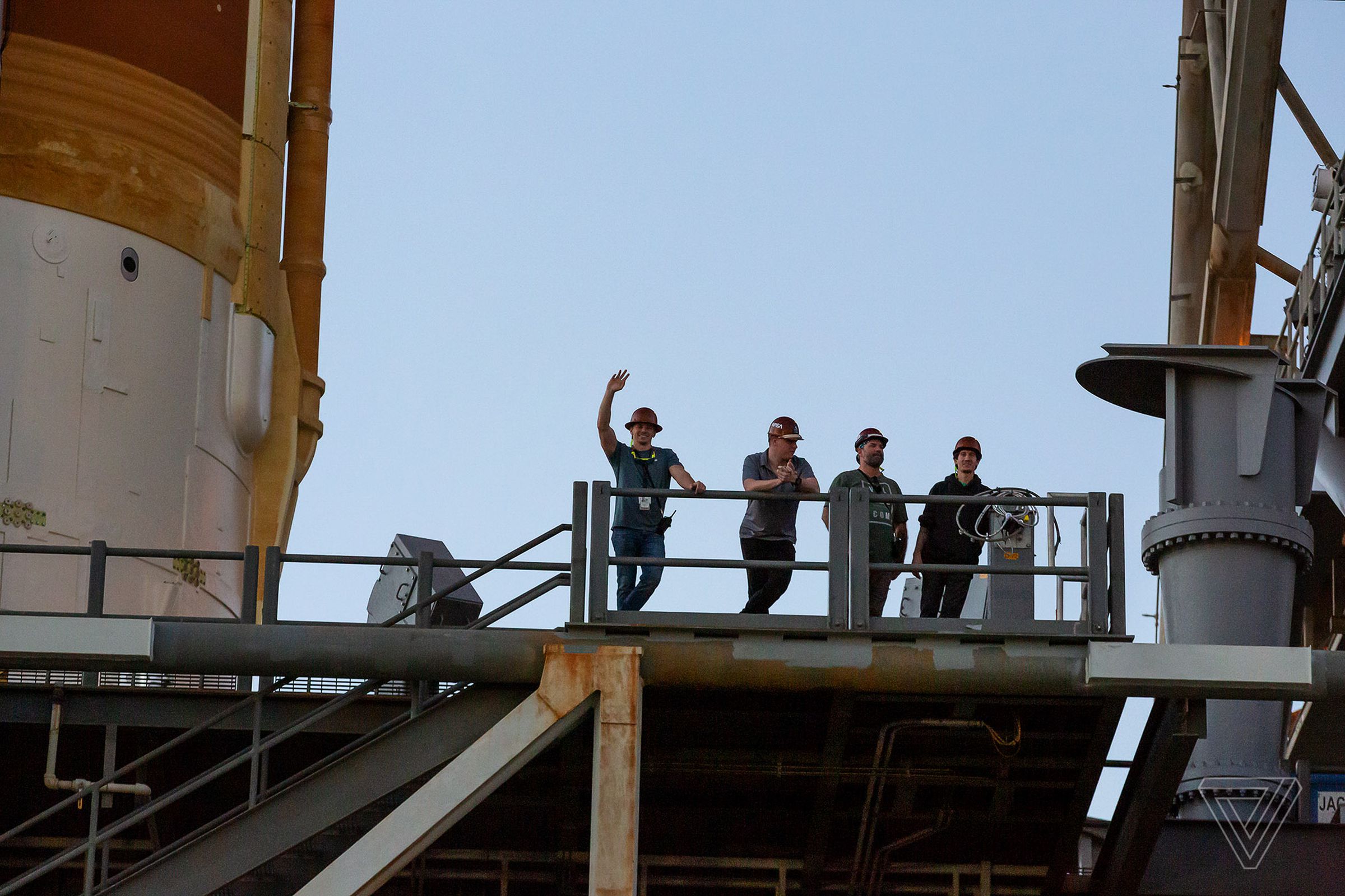 Workers on the mobile launch platform wave to onlookers.