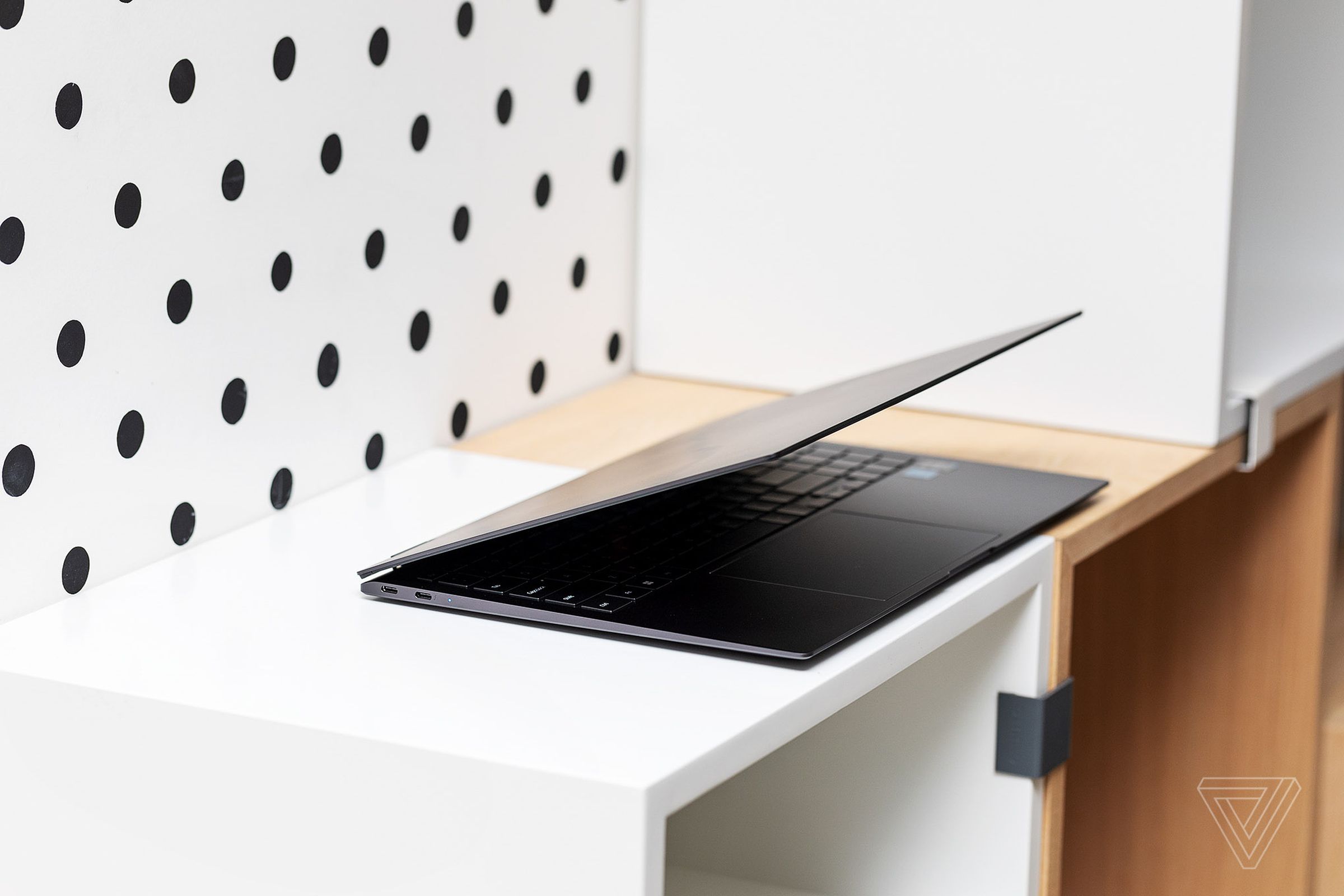 The Samsung Galaxy Book2 Pro 360 half open in front of a polka dot wallpaper.