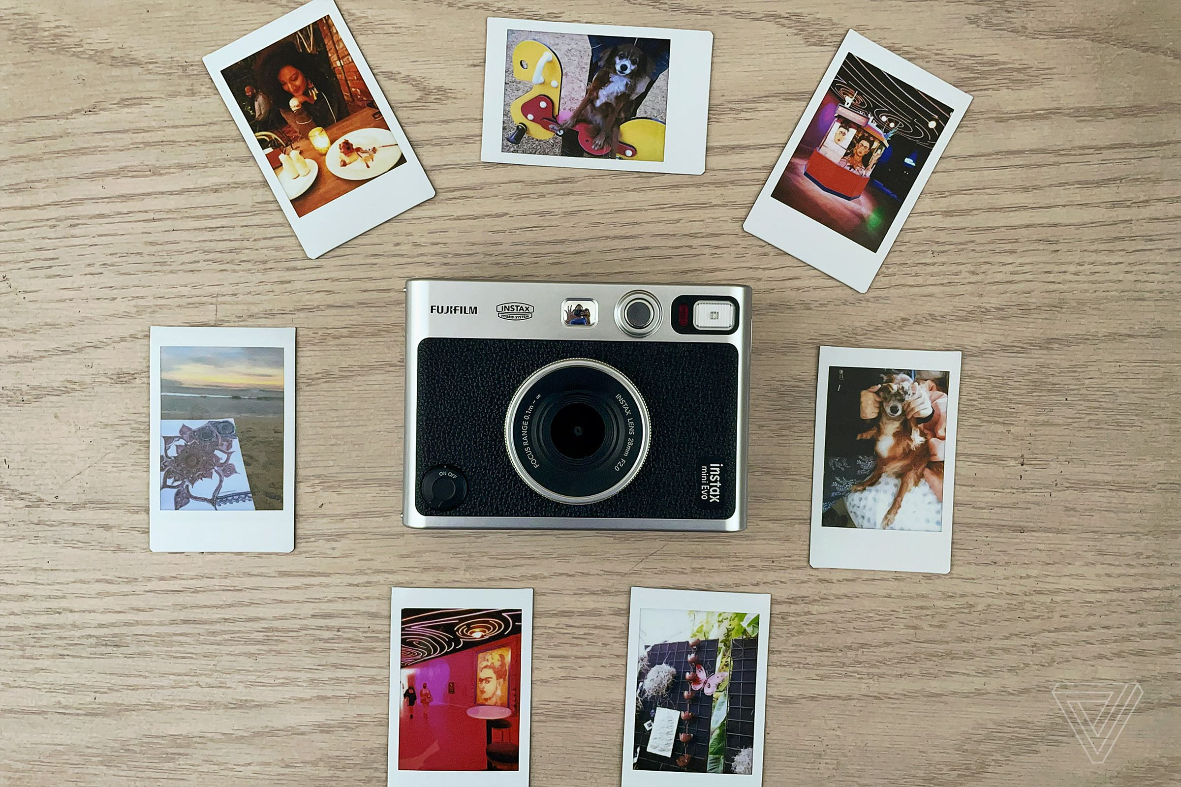 The Instax Mini Evo resting on a table surrounded by photos it’s produced.