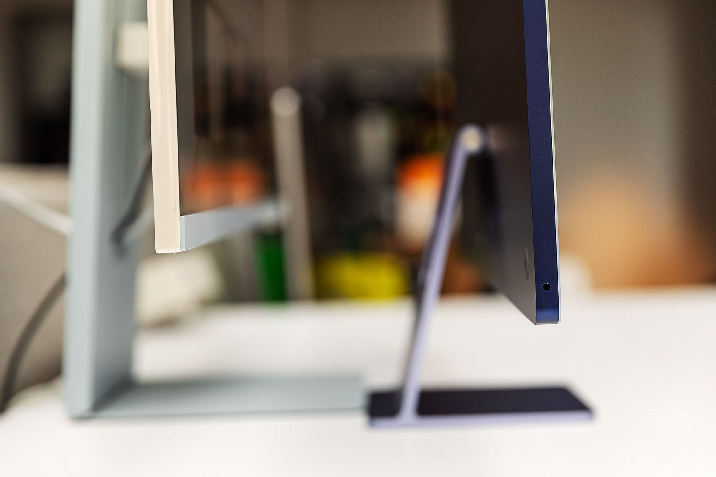 Side profile of the Samsung M8 and the Apple M1 iMac. The iMac has a much slimmer stand and display casing.