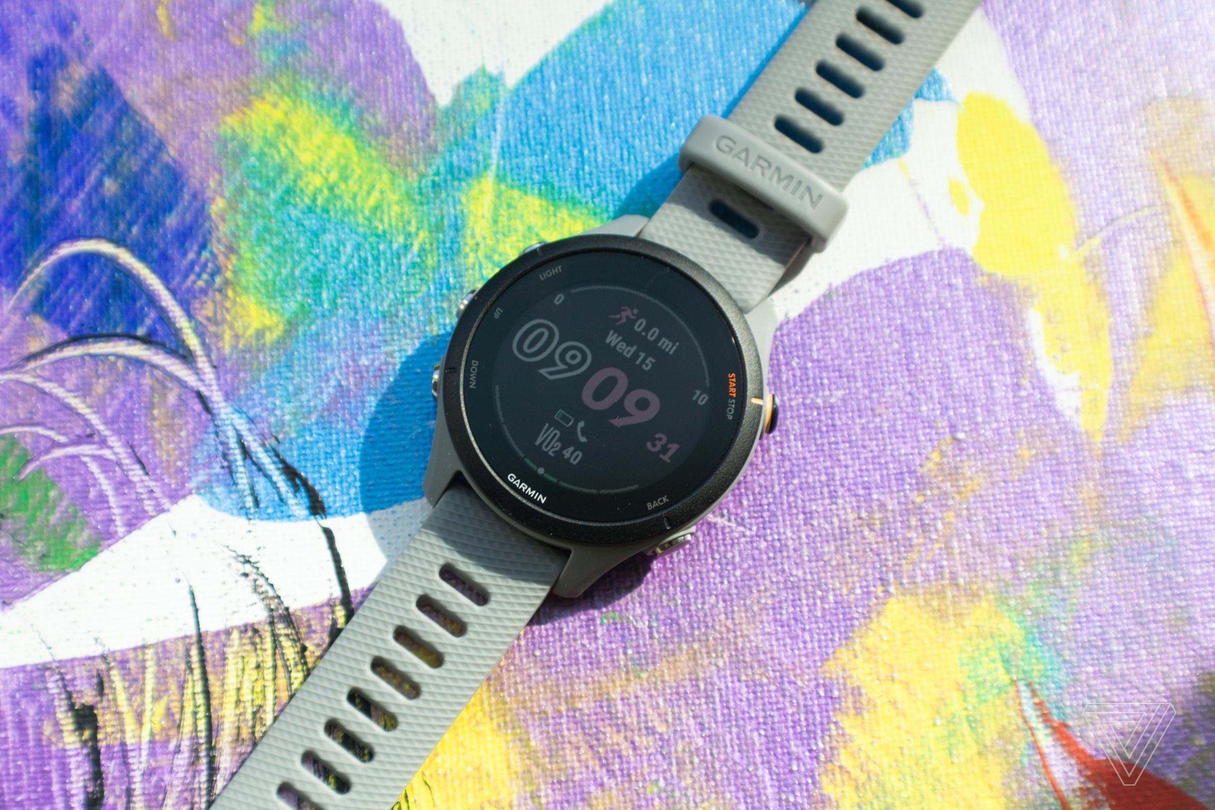 Garmin Forerunner 255S smartwatch on a colorful background