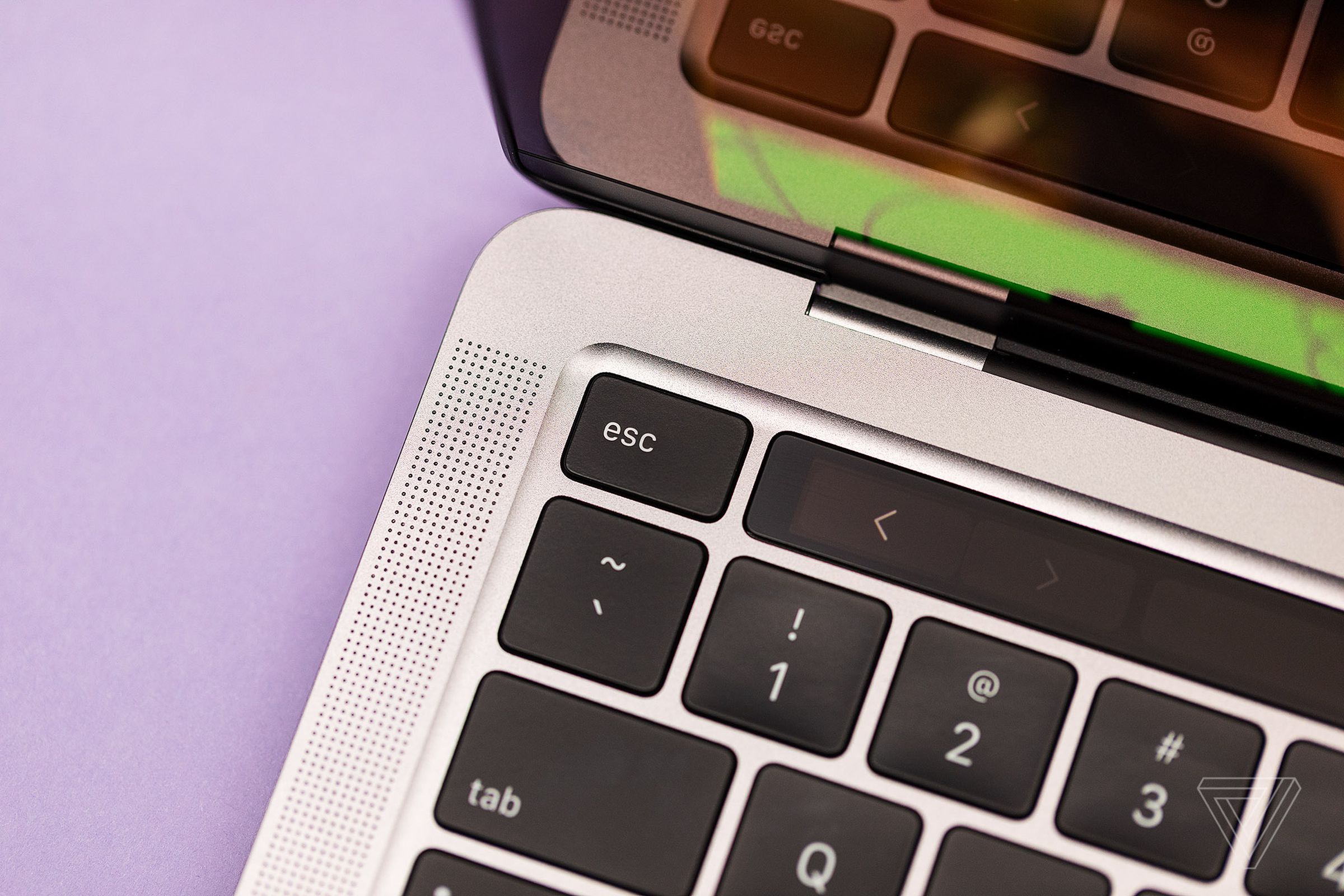 The top left corner of the Apple MacBook Pro 2022 keyboar deck on a lavendar background.