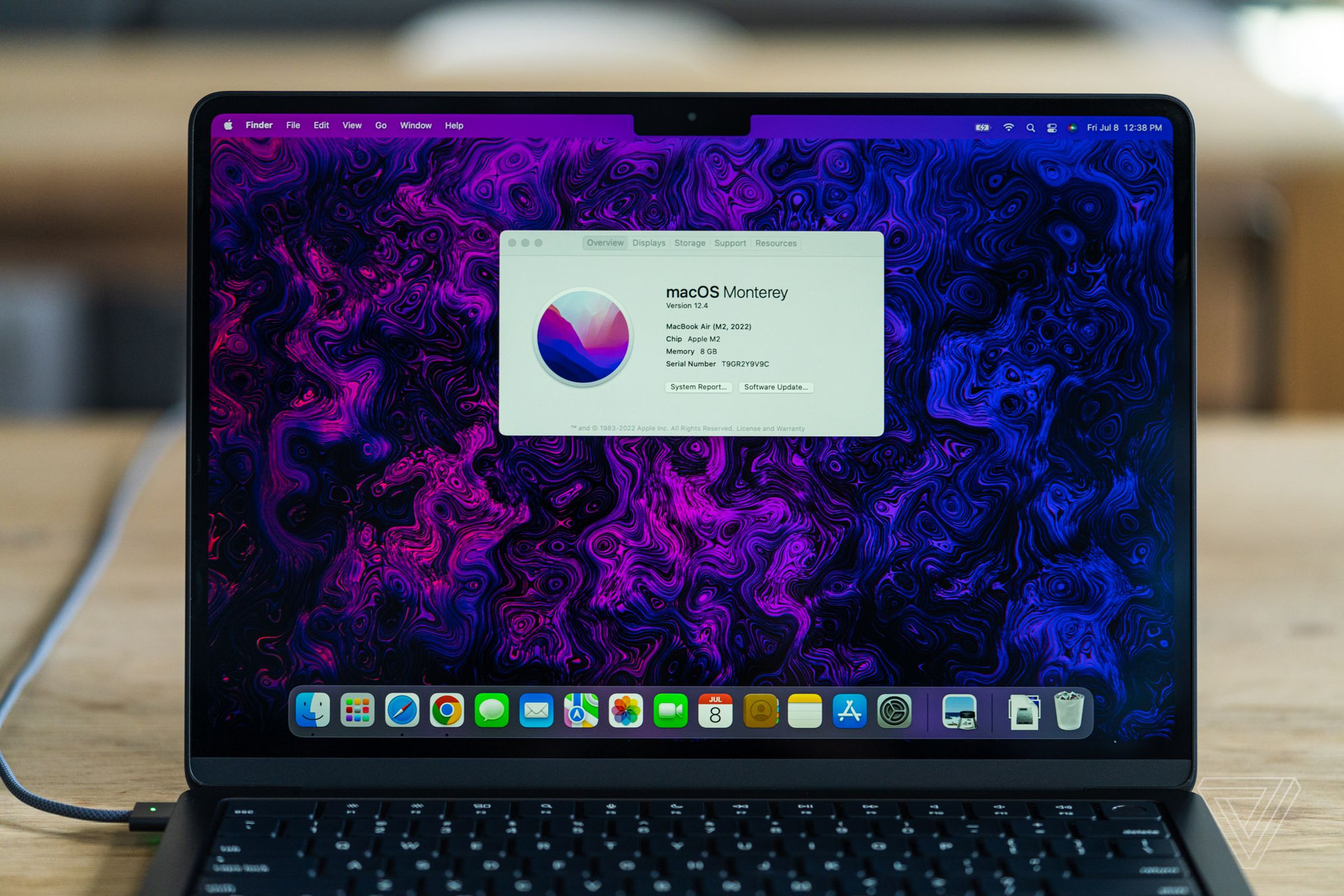 MacBook Air M2 на столе с окном «Об этом Mac» на фиолетовом мраморном фоне.