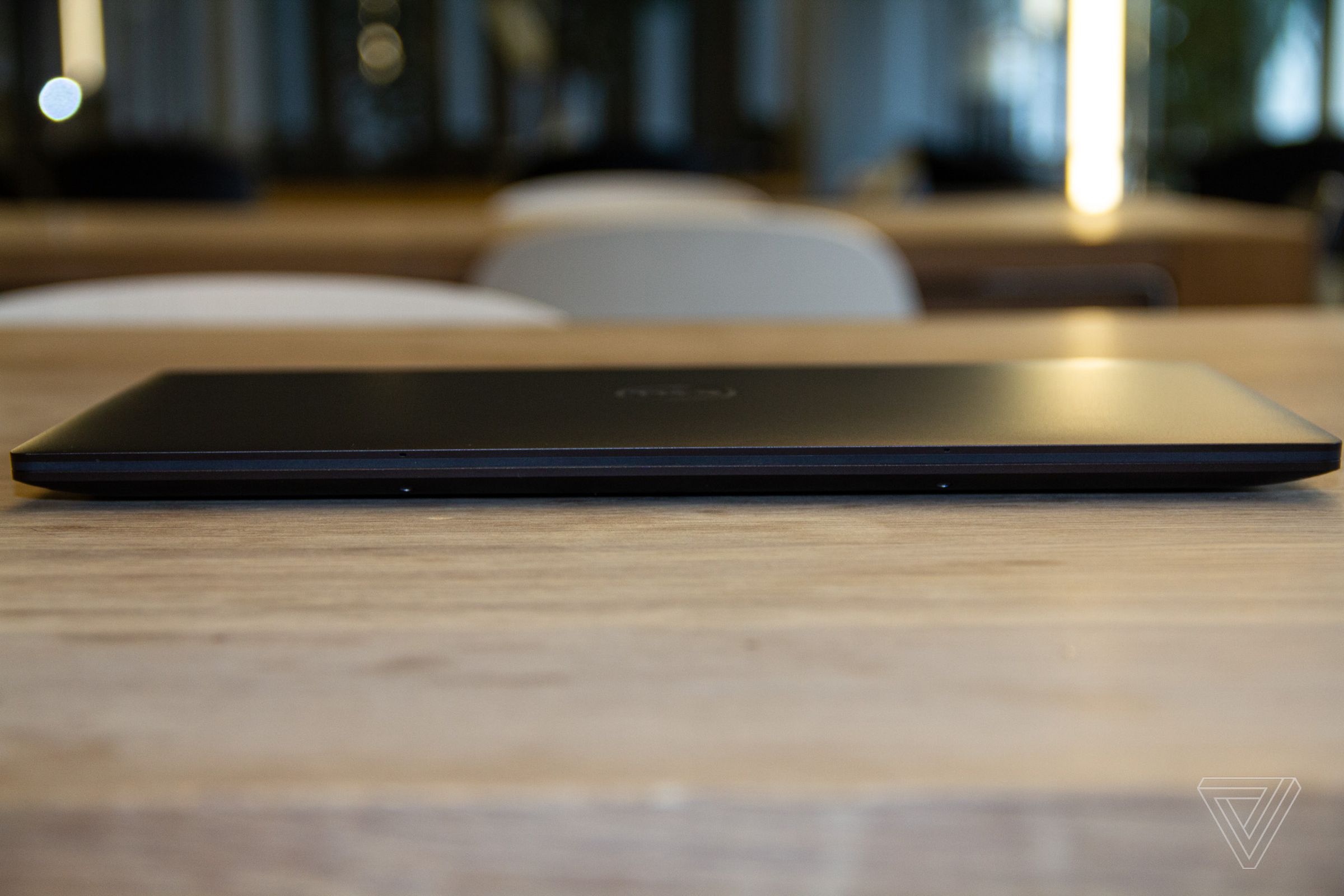 The Dell XPS 13 Plus closed on a wooden table seen from the front.