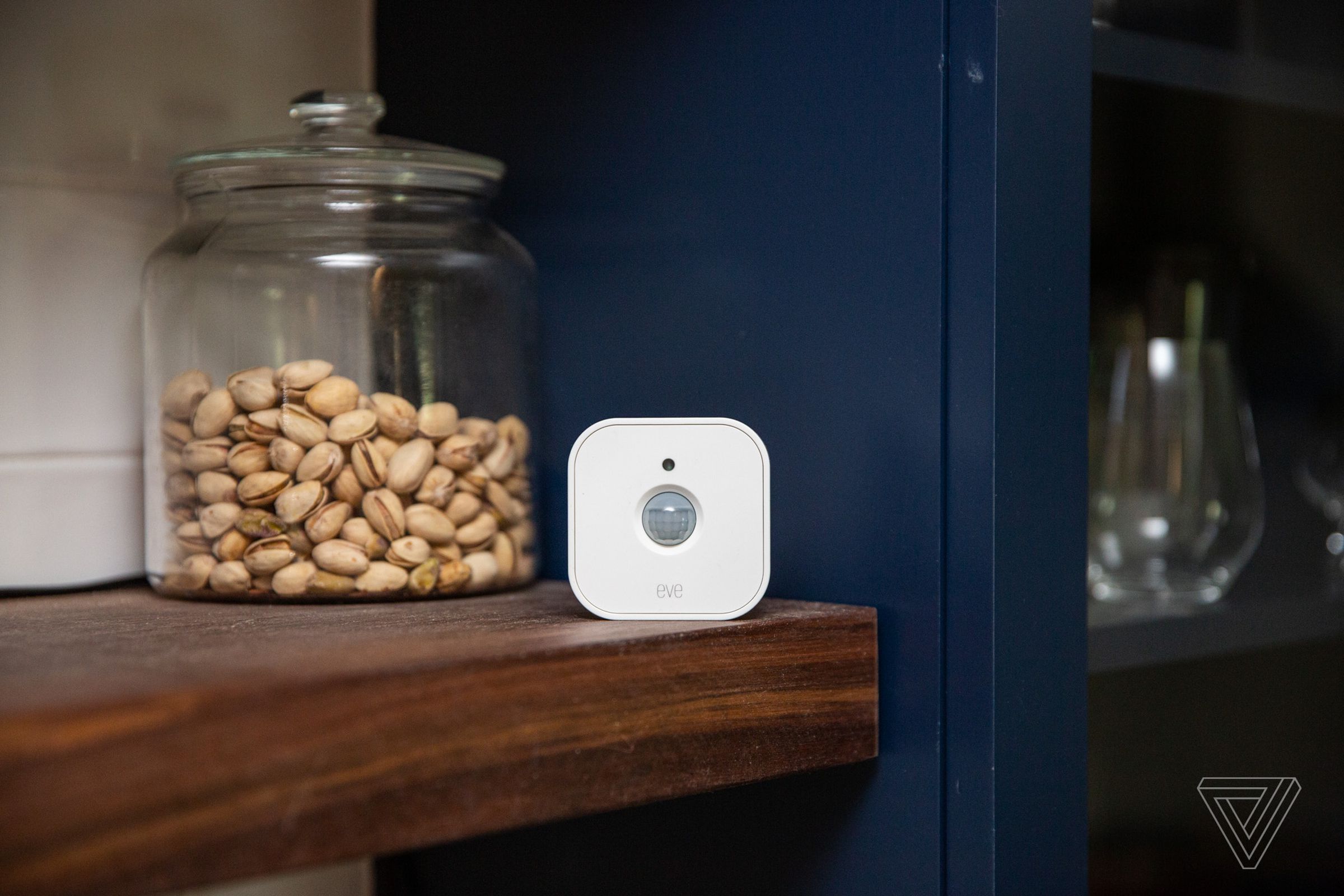 A white motion sensor on a shelf in a kitchen.