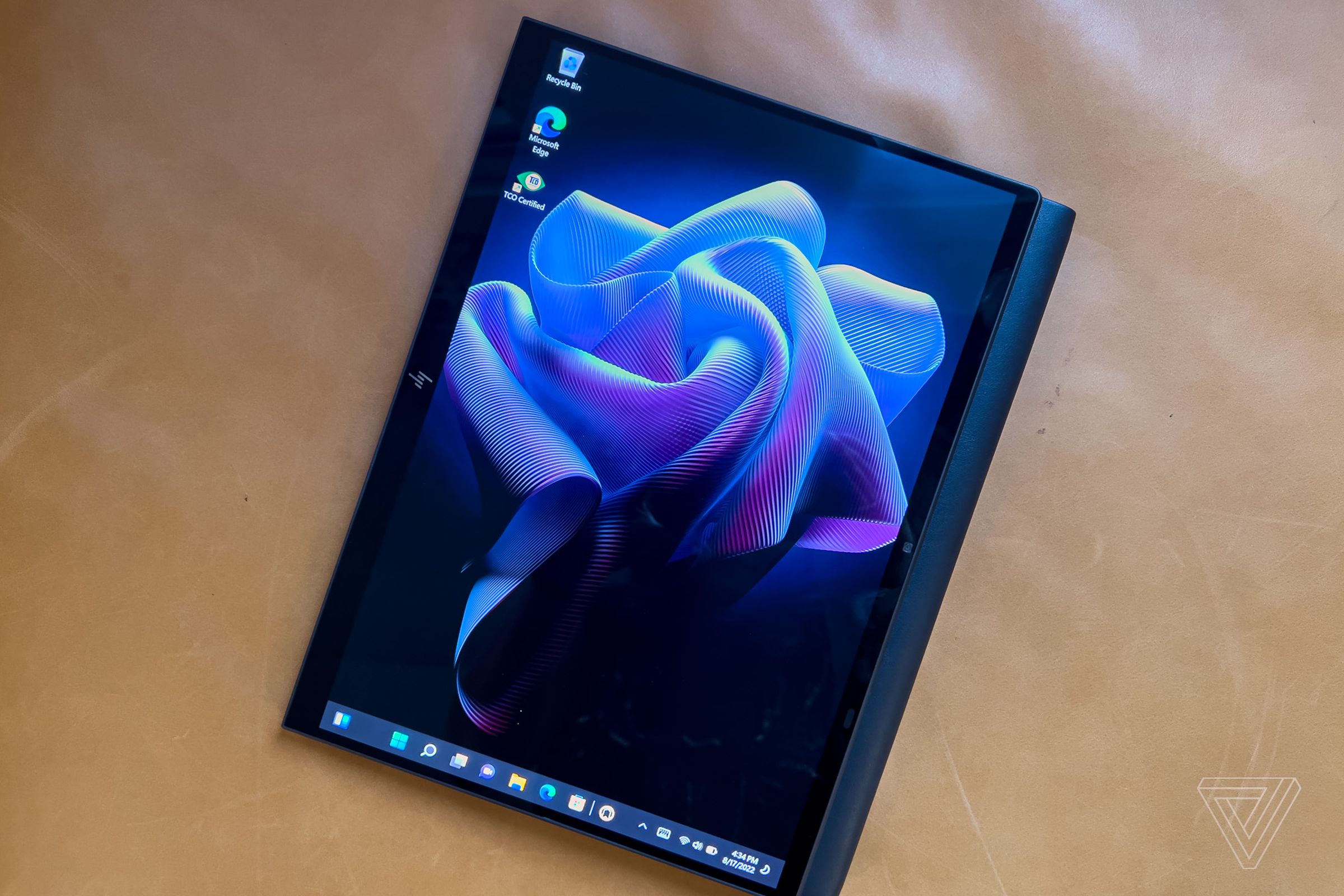 The HP Dragonfly Folio G3 in tablet mode seen from above. Screen displays a purple flower on a black background.
