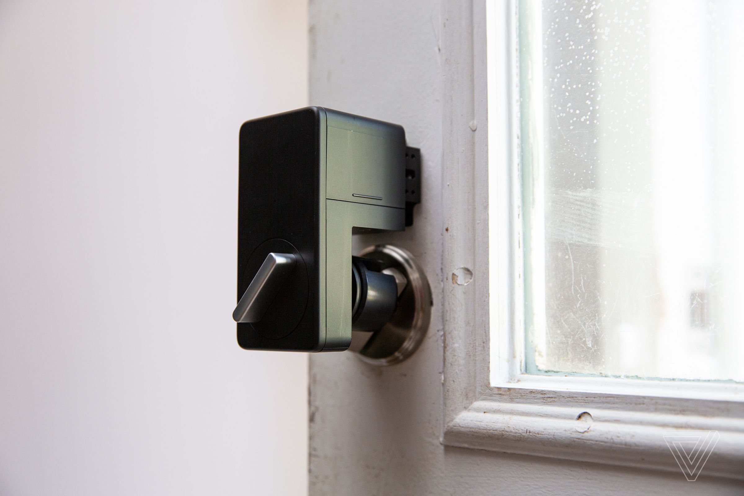 A black plastic motor attached to a thumb turn on a door