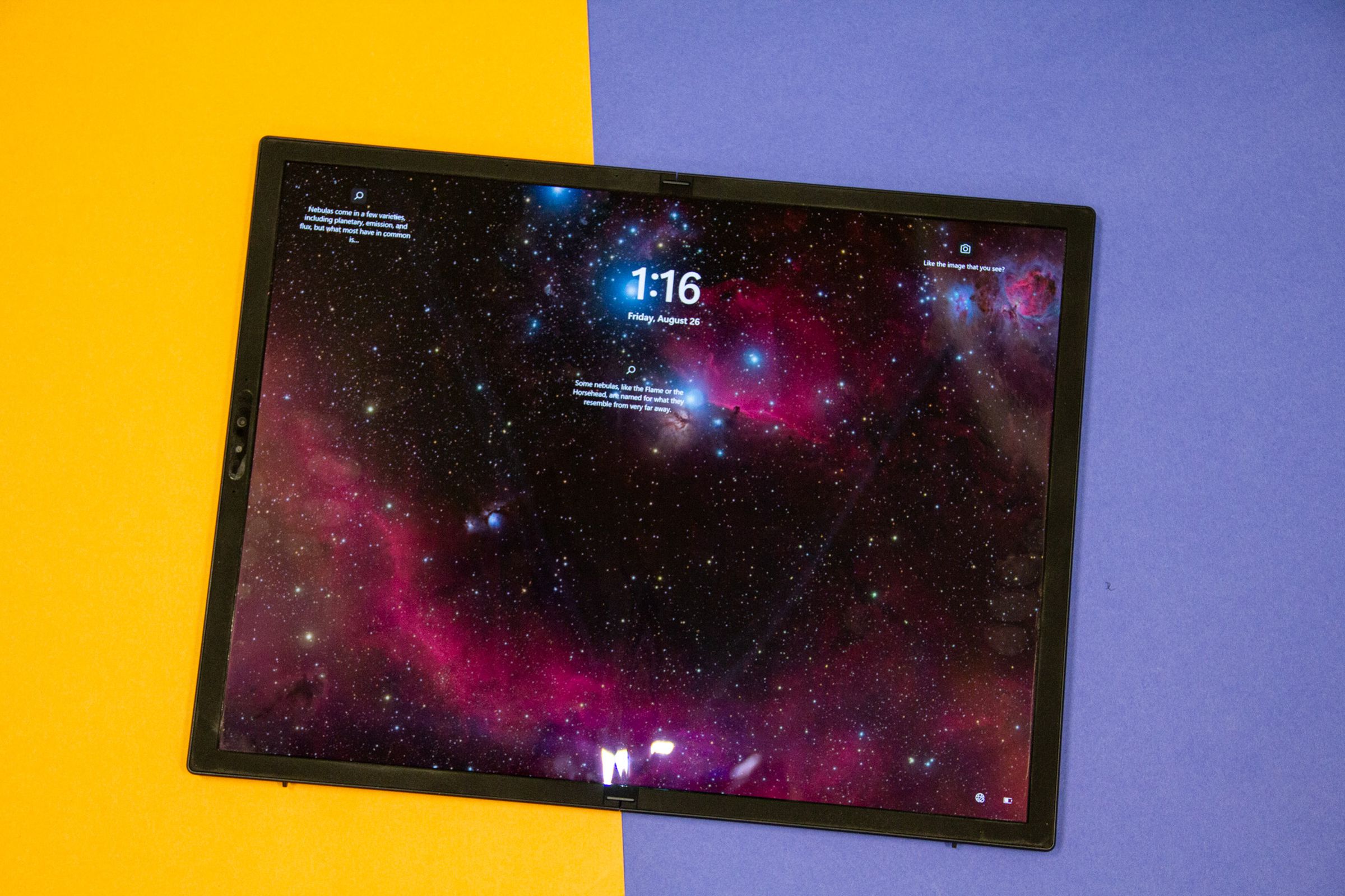 The Asus Zenbook 17 Fold OLED laid out in tablet mode, seen from above. The screen displays a picture of a galaxy and the time 1:16.