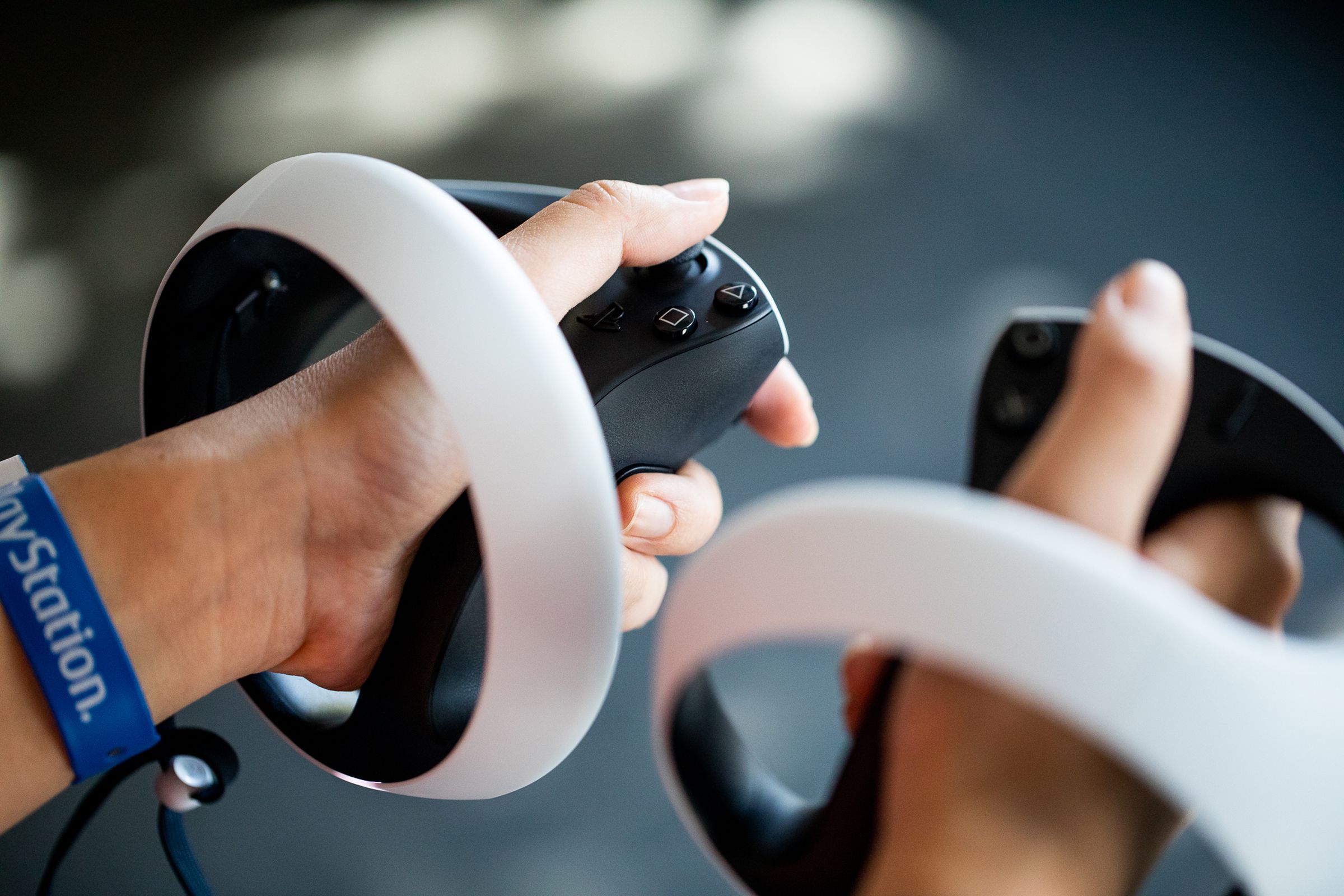 A person holds the left and right PSVR2 Sense controllers in their hands.