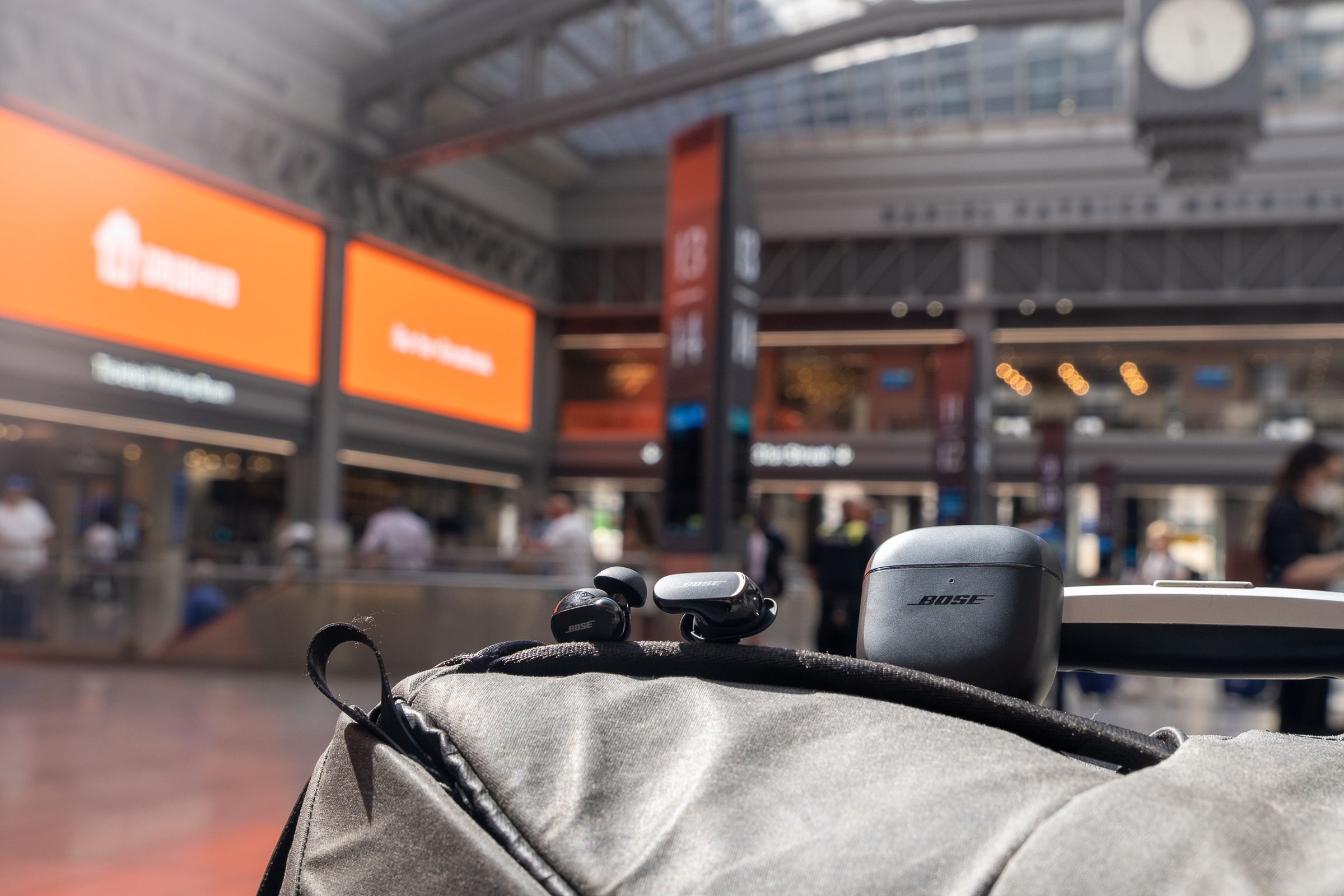 The Bose QC Earbuds II pictured on top of a backpack at Moynihan Train Hall in New York City.