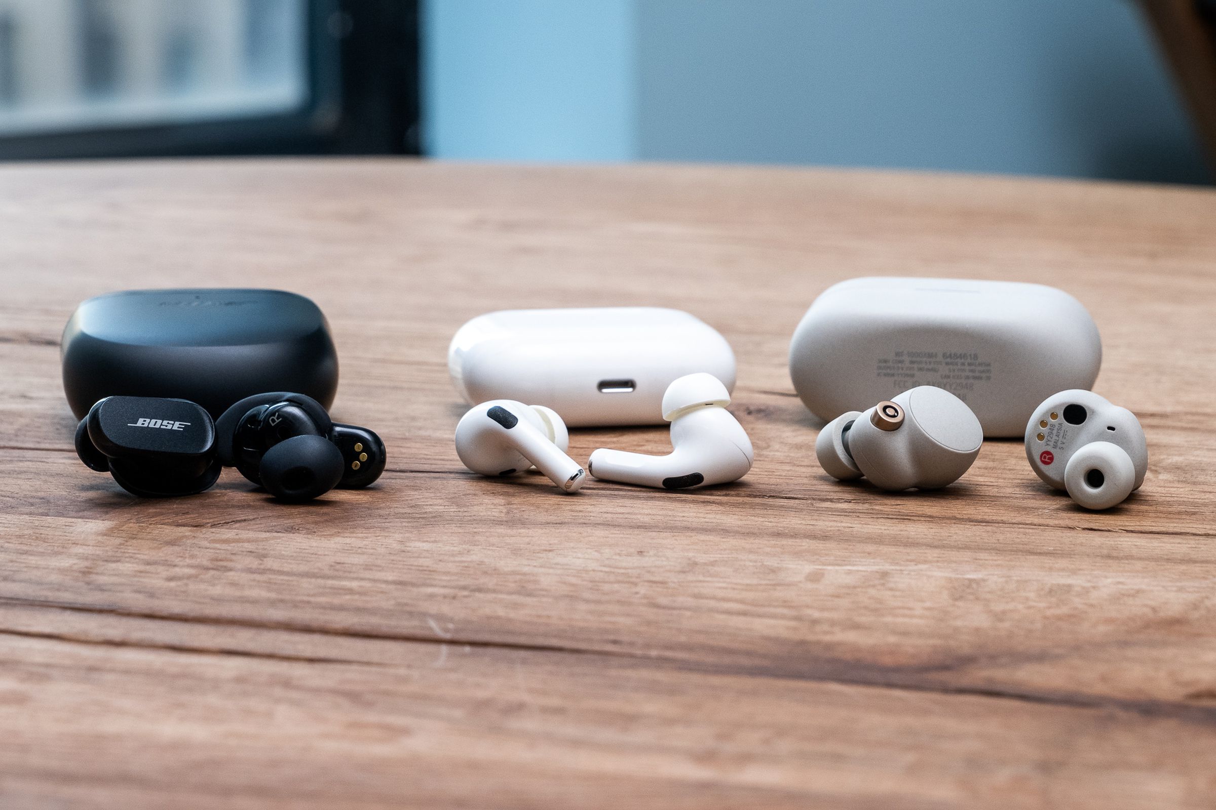 A side-by-side comparison photo of Bose’s QuietComfort Earbuds II, Apple’s AirPods Pro, and Sony’s WF-1000XM4.