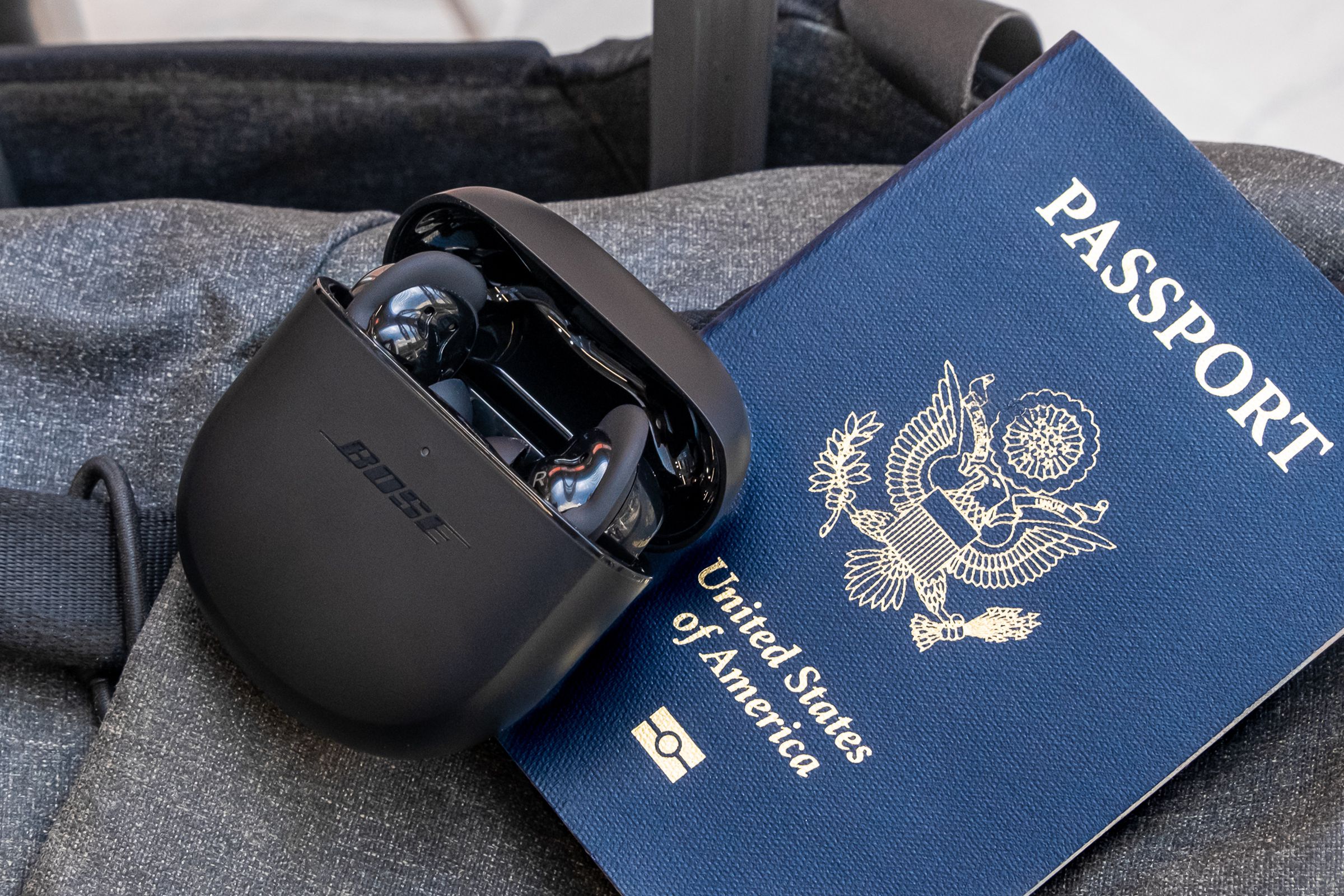 An image of the Bose QuietComfort Earbuds II with an open case next to a United States passport.