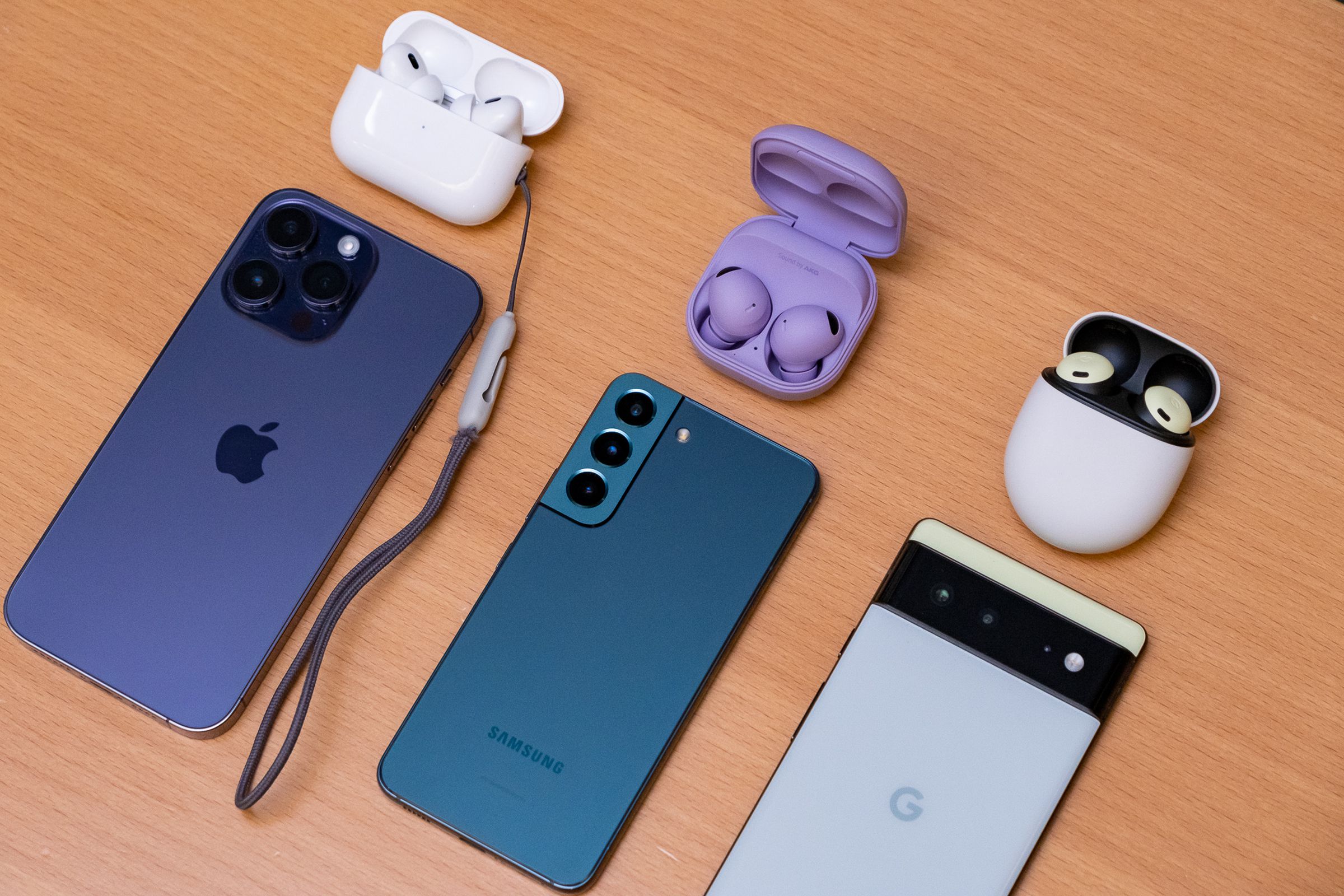 Apple’s second-generation AirPods Pro, Samsung’s Galaxy Buds 2 Pro, and Google’s Pixel Buds Pro pictured above the iPhone 14 Pro Max, Galaxy S22, and Pixel 6, respectively.