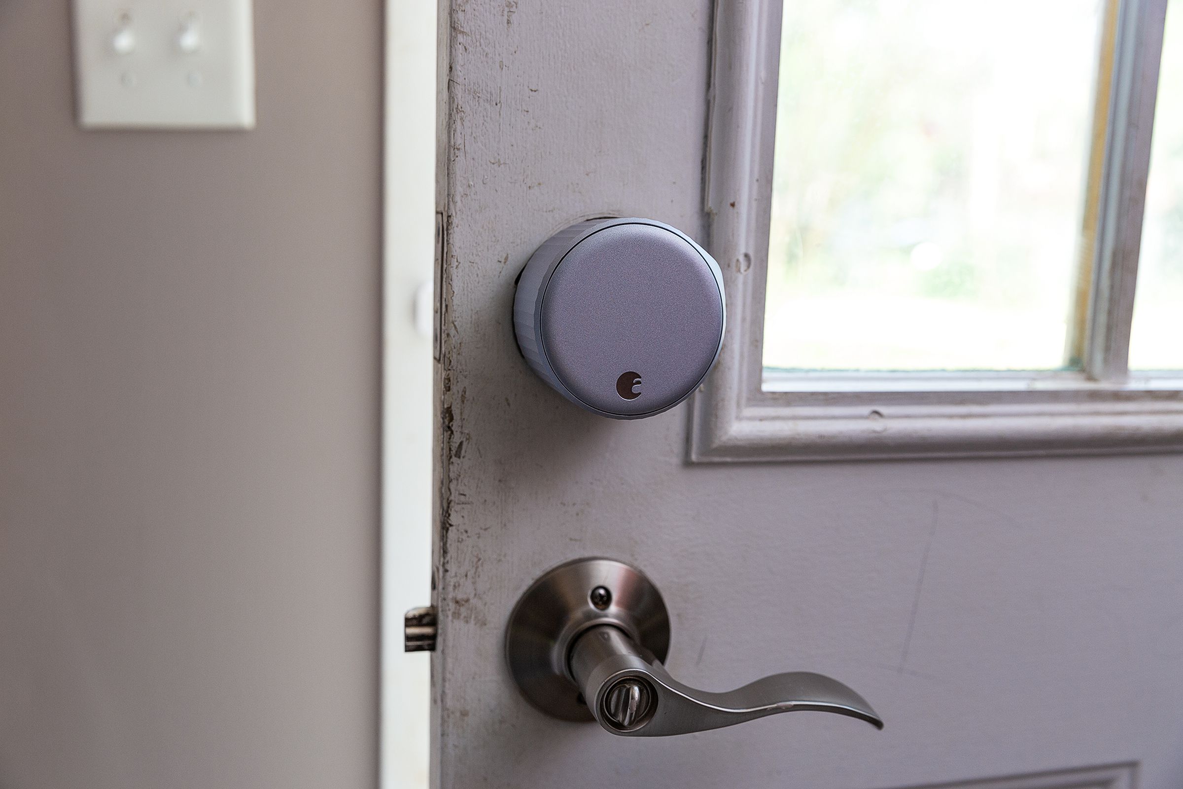 A large silver door lock on a door above a lever handle