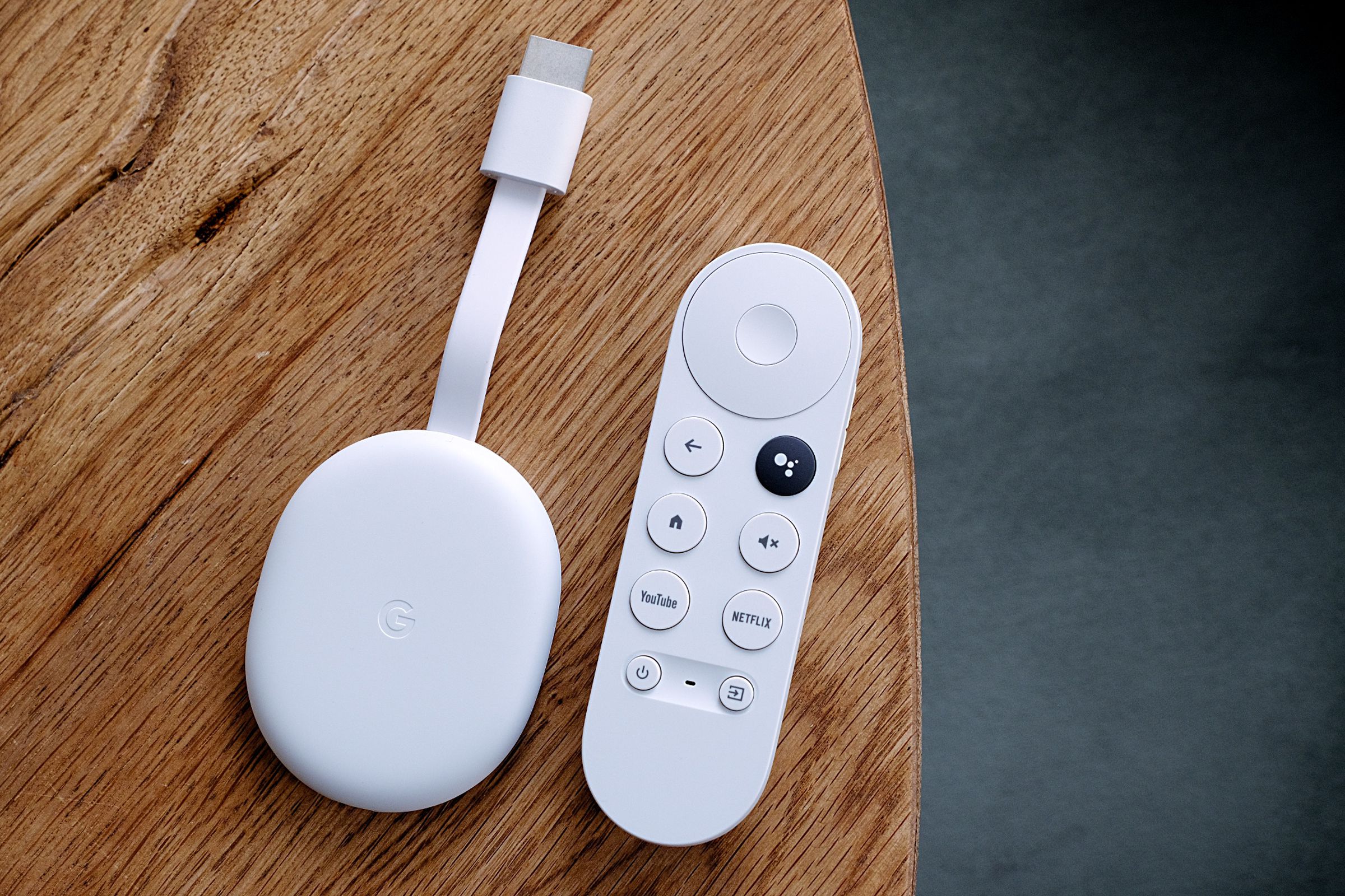 An overhead image of the Chromecast with Google TV HD and its remote on a wooden table.