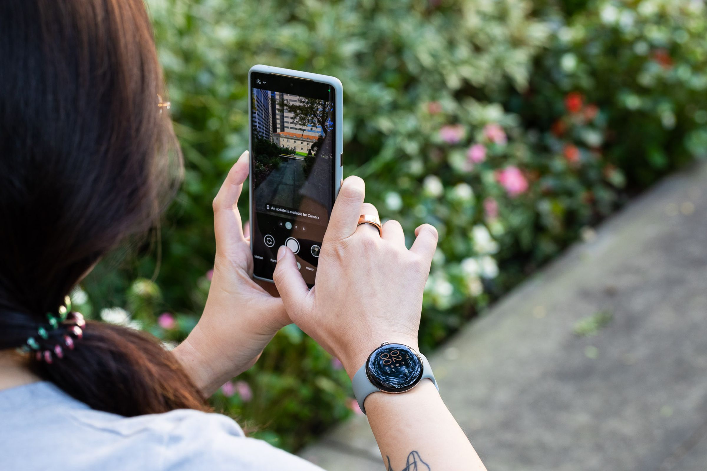 Woman wearing a Pixel Watch while taking a photo with the Pixel 7 Pro