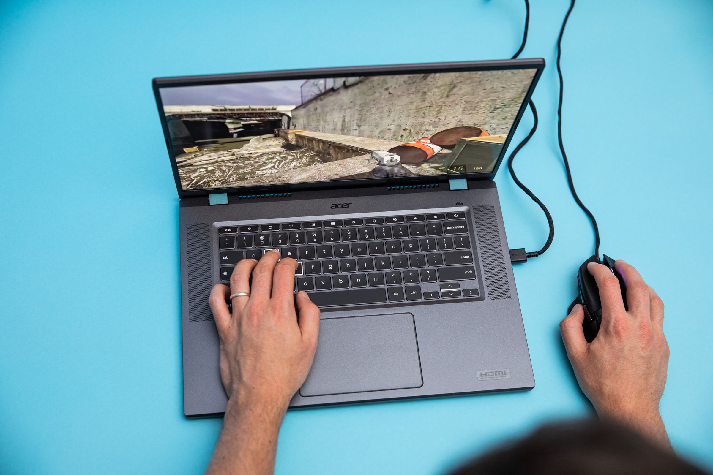 The Acer Chromebook 516 GE with a mouse plugged in, playing Half Life 2. The author’s left hand is placed on the laptop’s W, A, S, and D keys to move around.