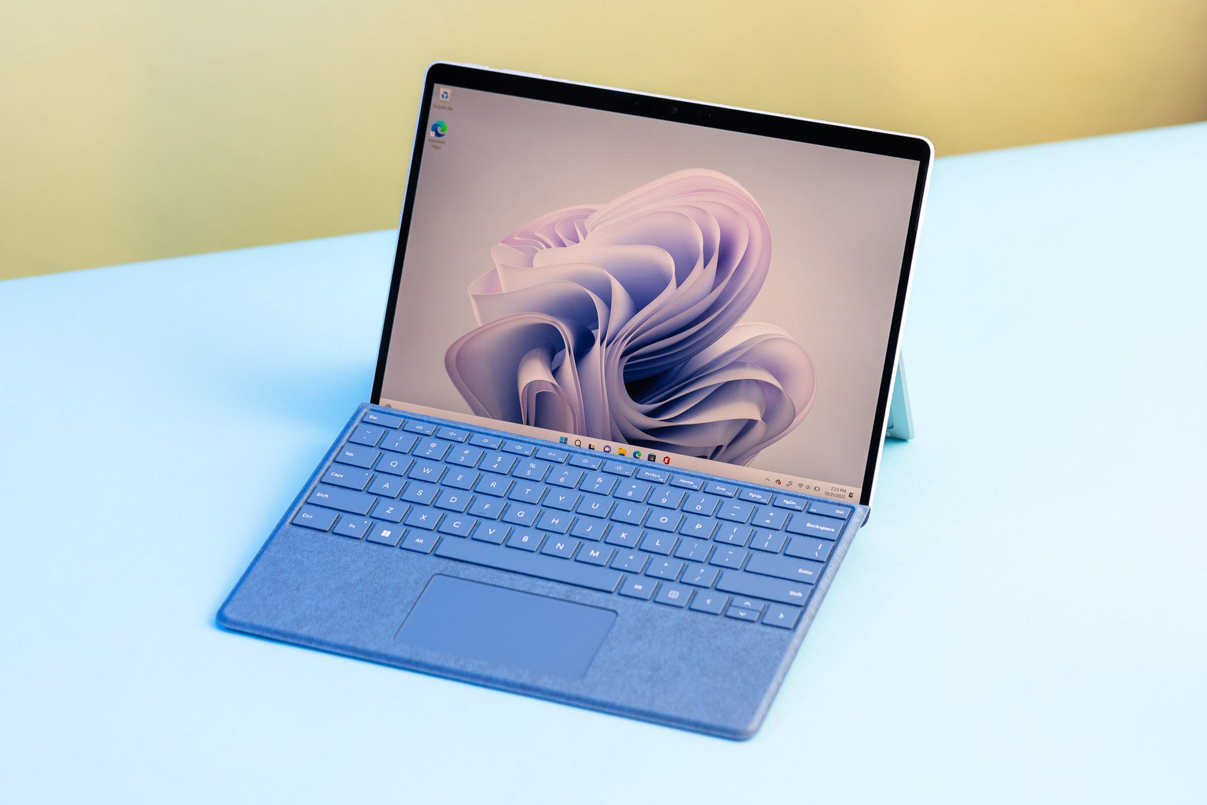 Dizüstü bilgisayar modundaki Surface Pro 9 yukarıdan görülüyor. Ekran, açık mavi kurdeleli bir masaüstü arka planı görüntüler.