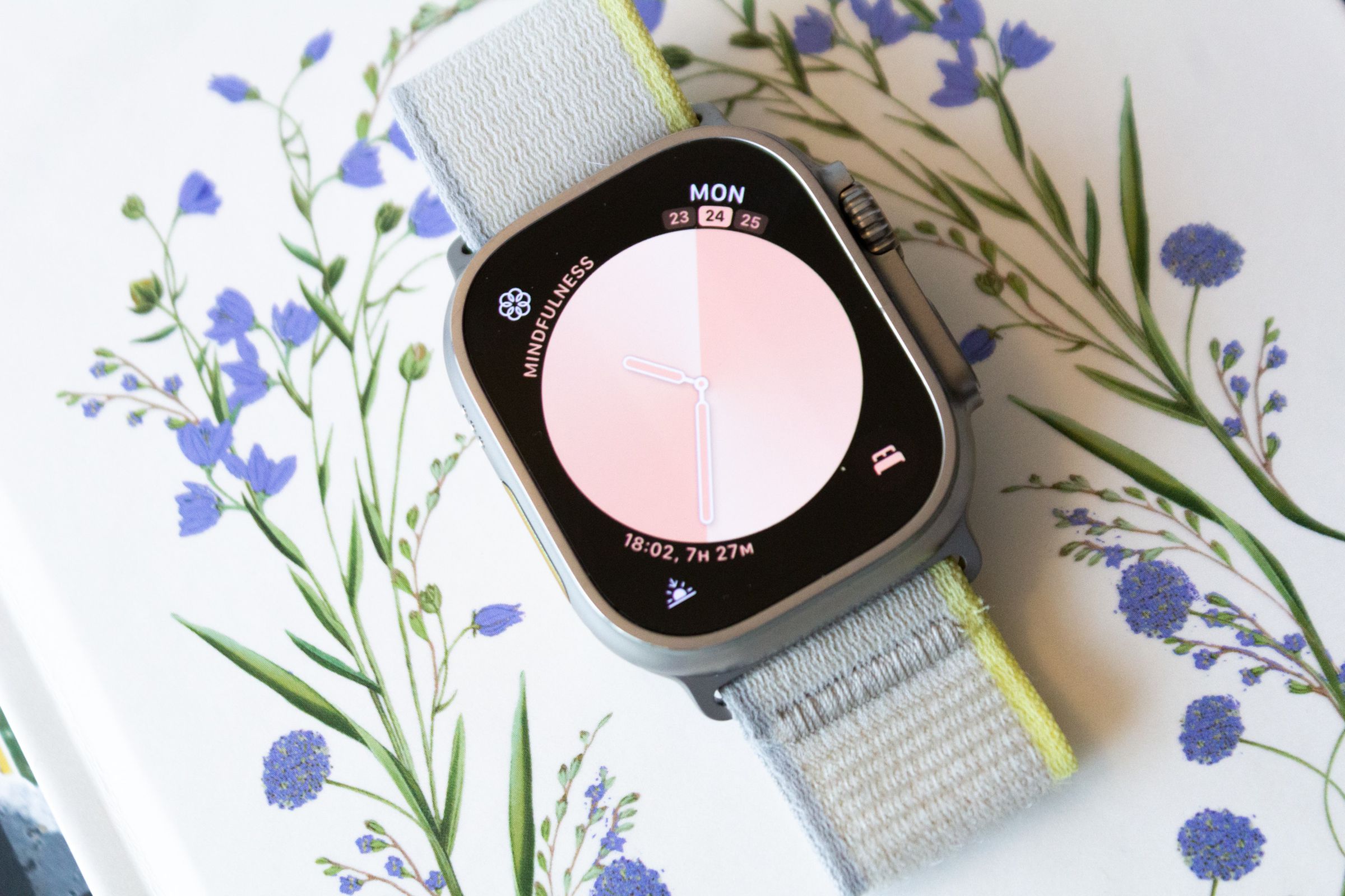 An Apple Watch Ultra lying on a floral patterned surface.