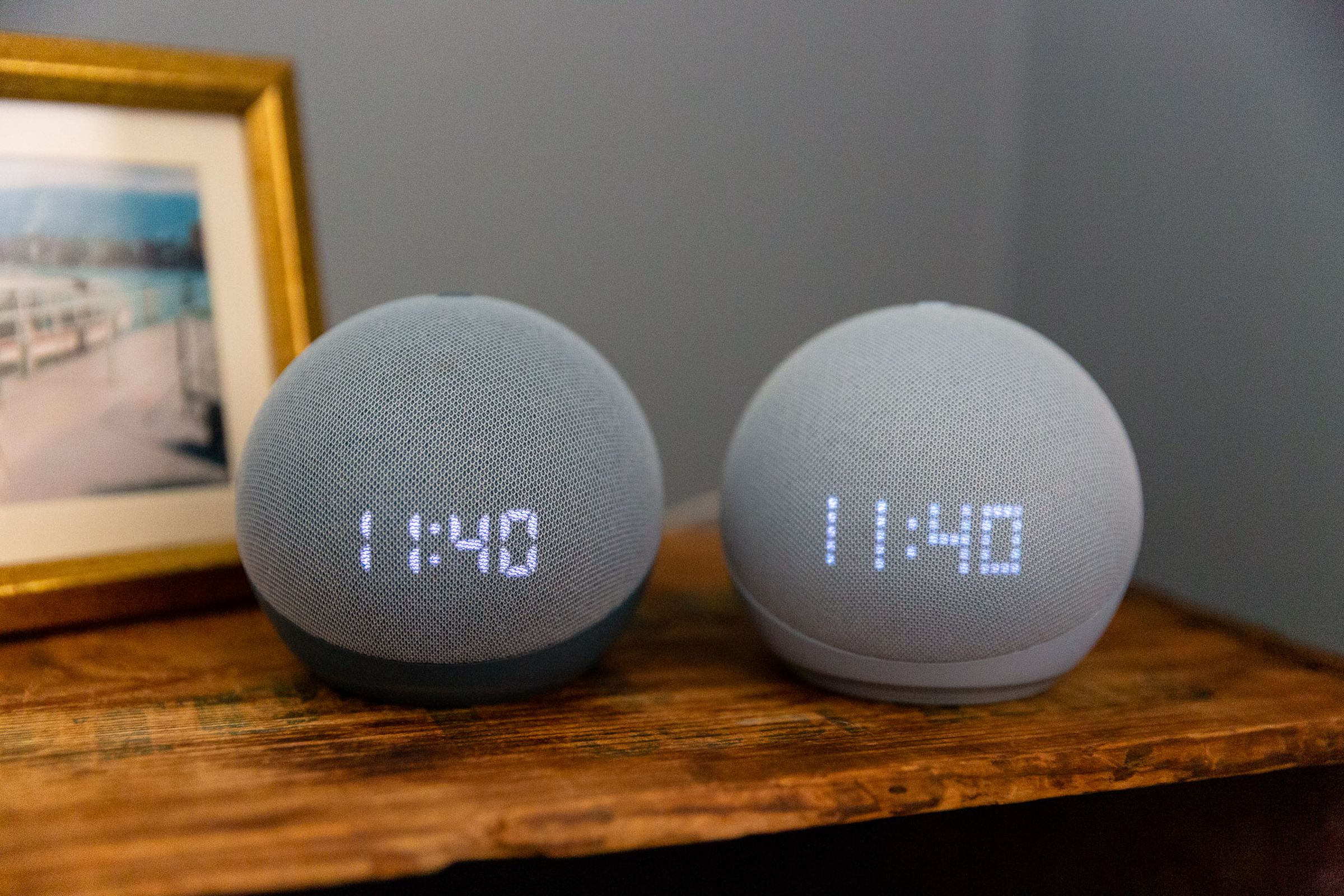 Two Echo Dot with Clock speakers on a bedside table.