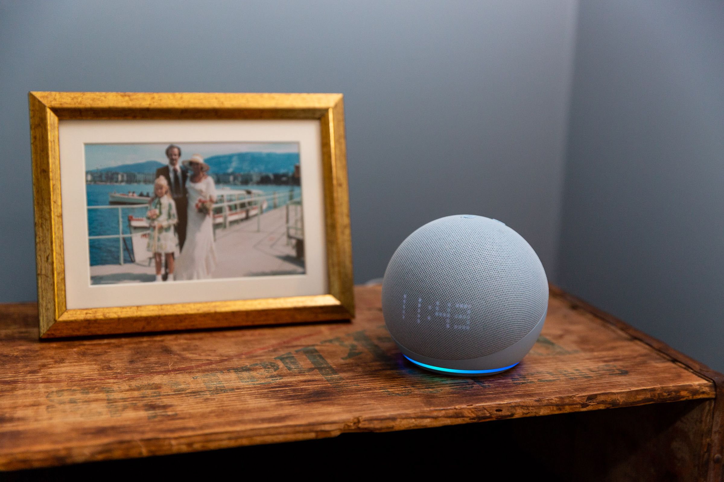 An Echo Dot on a bedside table next to a framed photograph