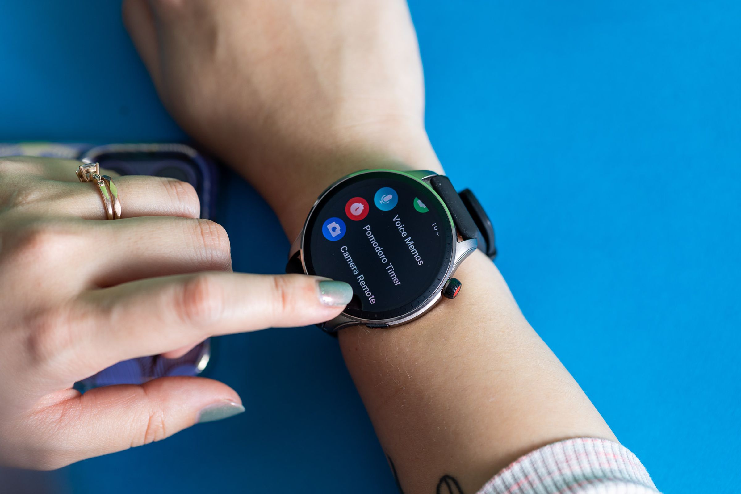 Amazfit GTR 4 on a woman’s wrist, displaying the Camera Remote and Pomodoro Timer app in a menu list.