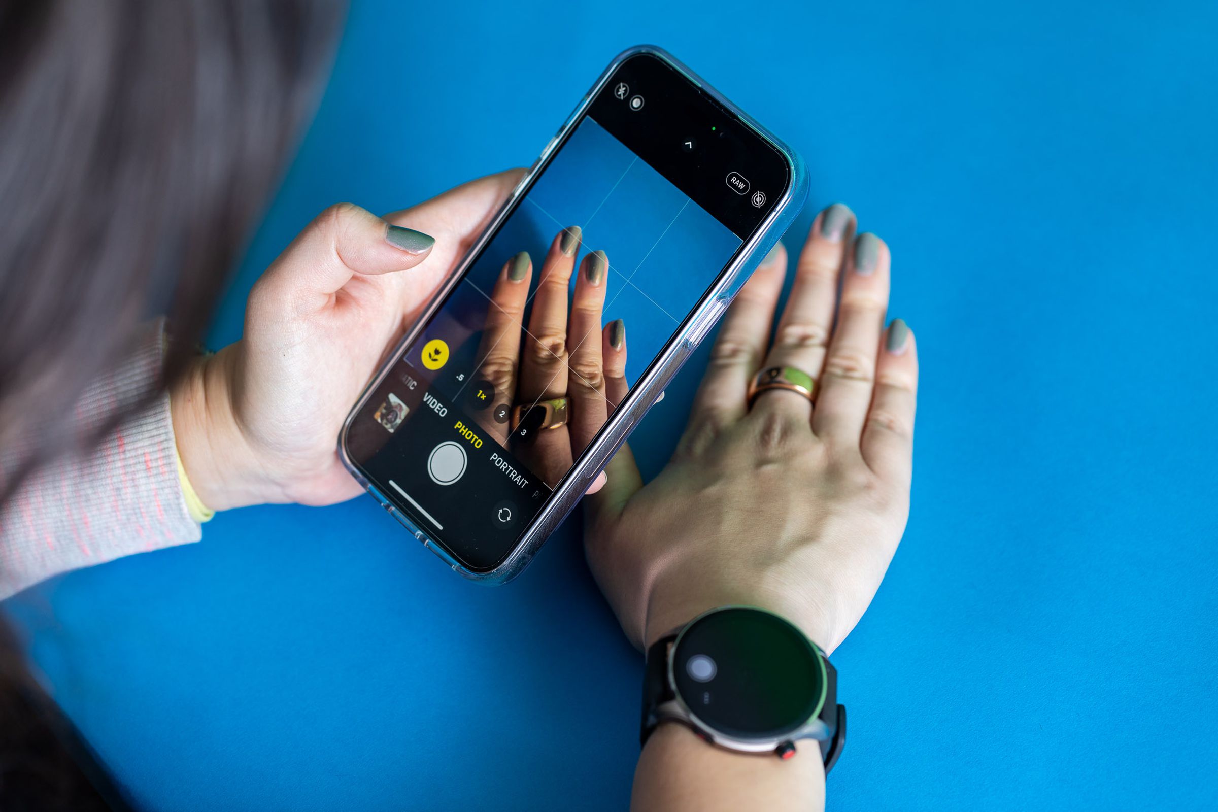 Woman using iPhone camera while the camera remote app is visible on the Amazfit GTR 4.