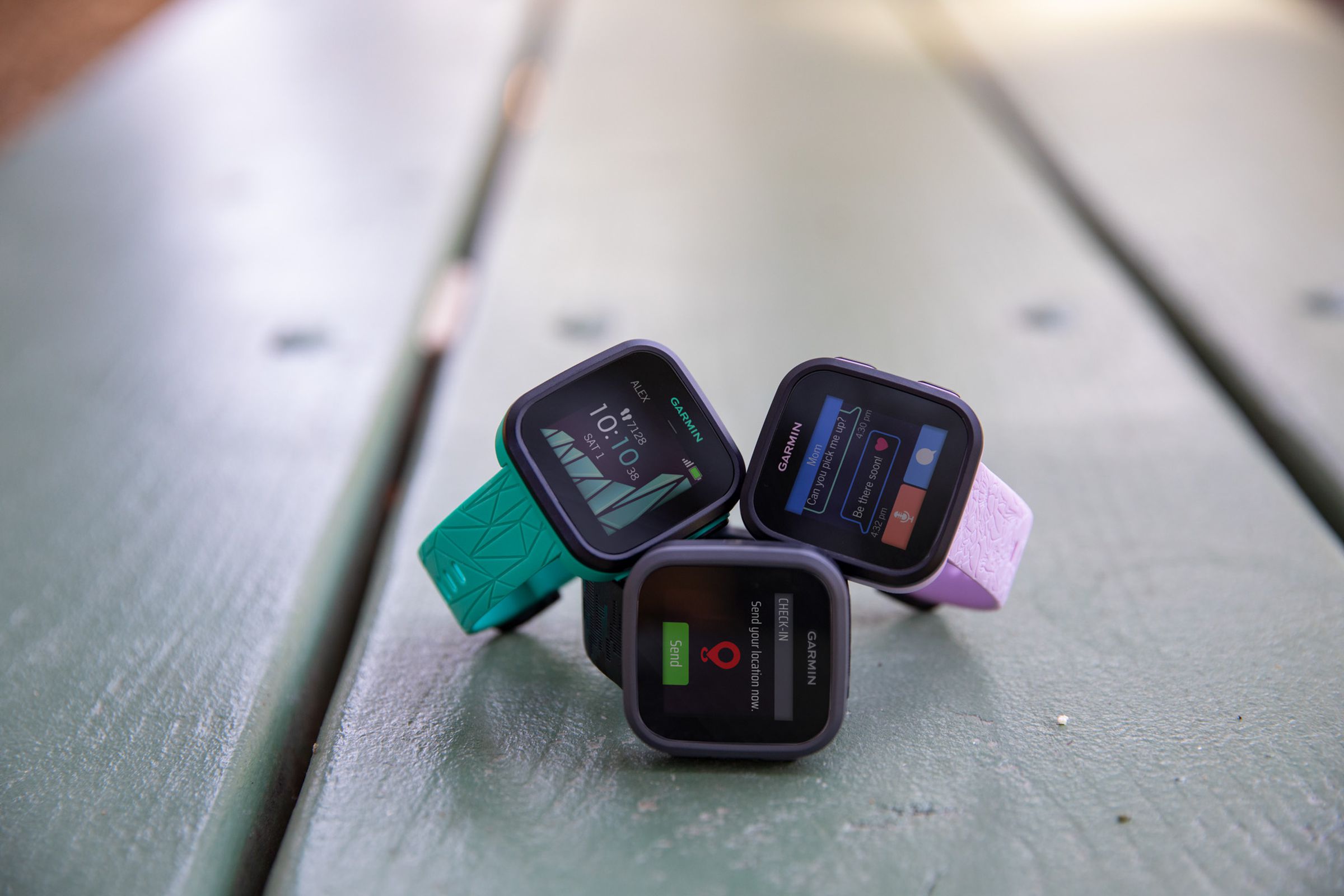 The green, black, and lilac versions of the Garmin Bounce on a wood table.